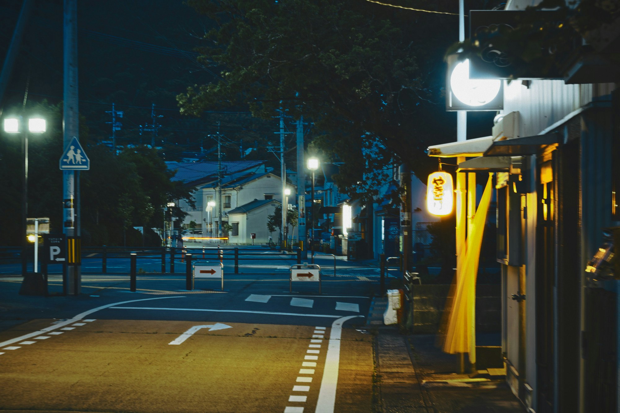 夜の街角の街灯と横断歩道のある通り