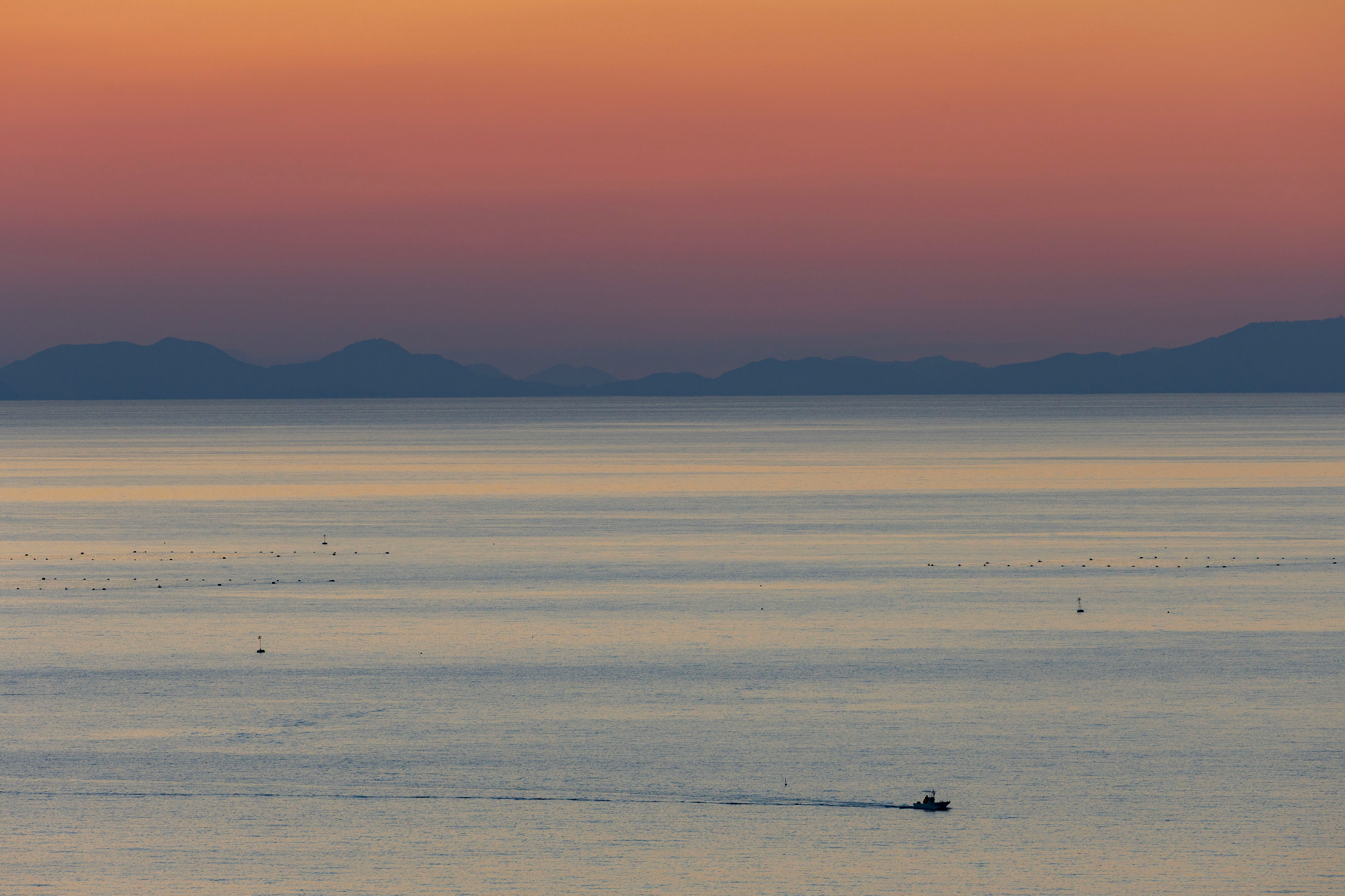 夕暮れの広い砂浜と水平線、遠くの山並み