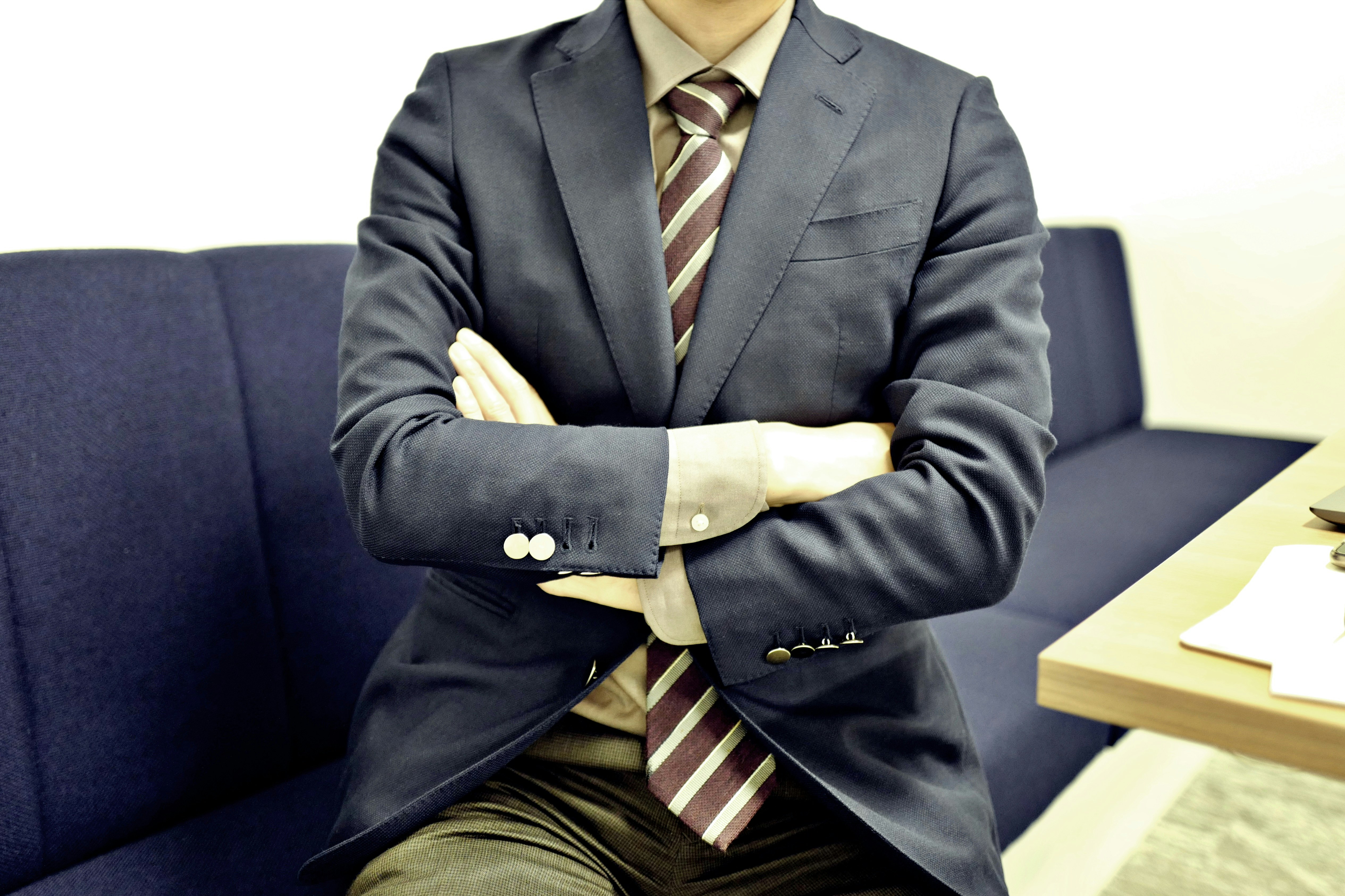 穿西裝的商務人士坐在沙發上雙臂交叉