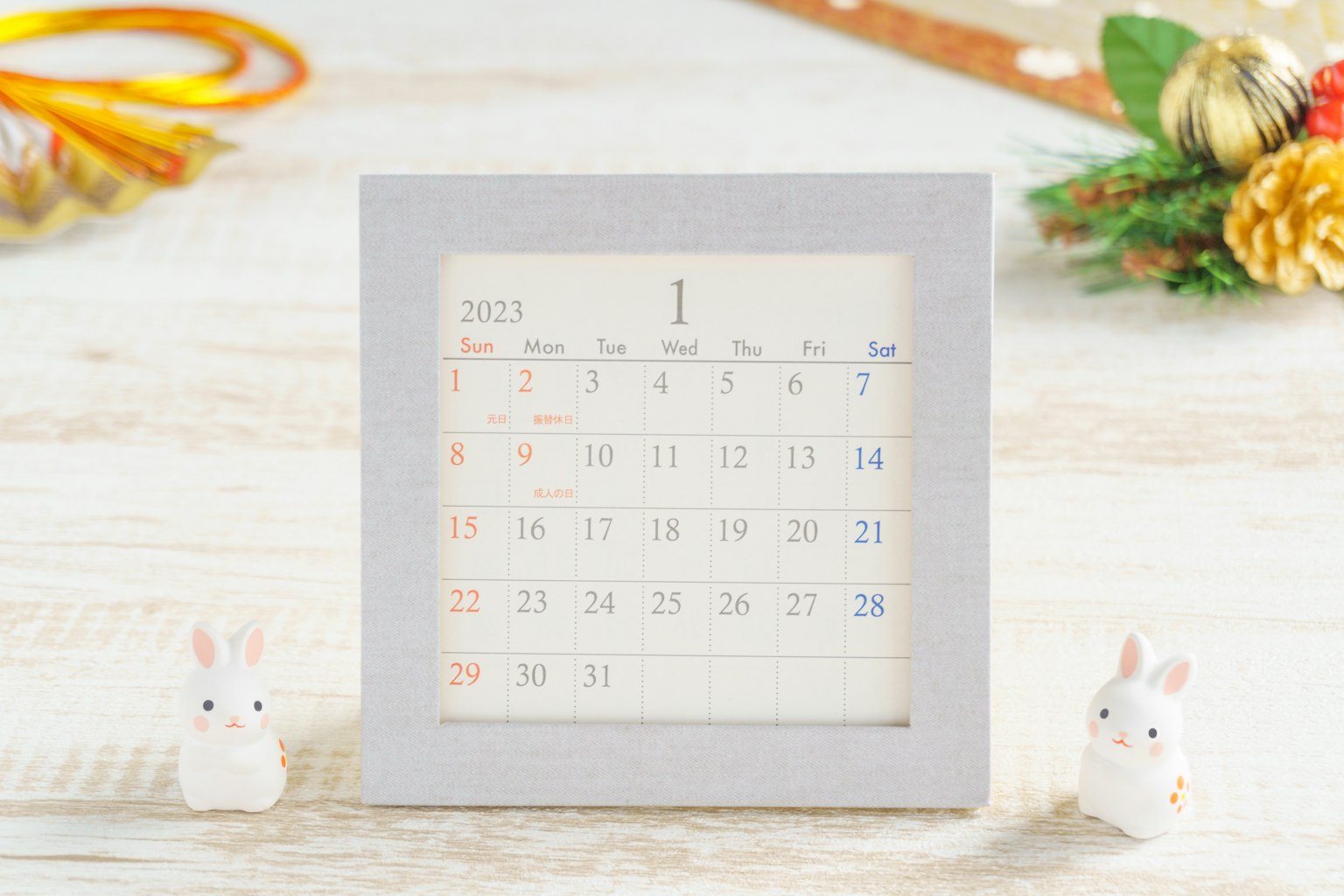 Un calendario con marco blanco y figuritas de conejo sobre una mesa de madera