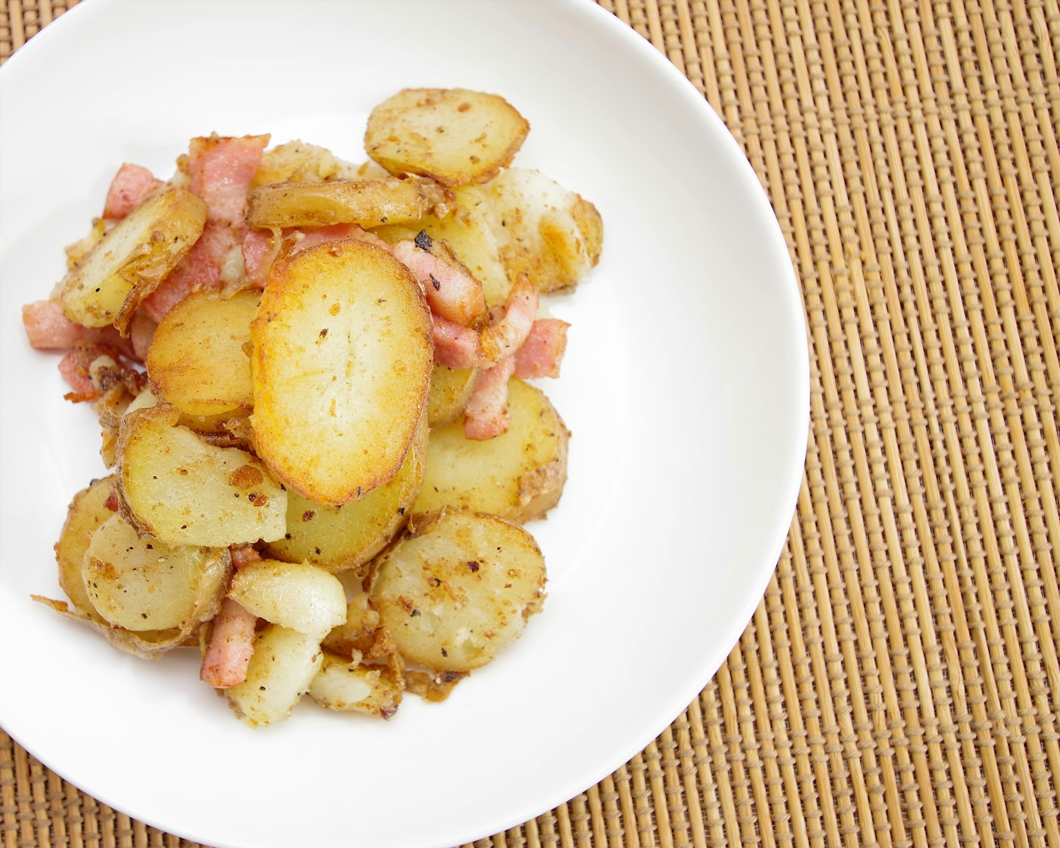 Crispy bacon and roasted potatoes served on a white plate