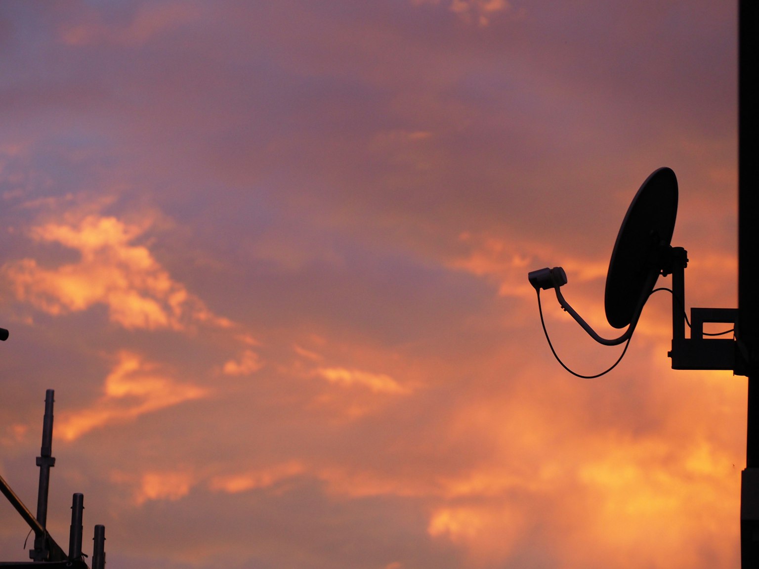 Silueta de una antena satelital contra un cielo de atardecer colorido