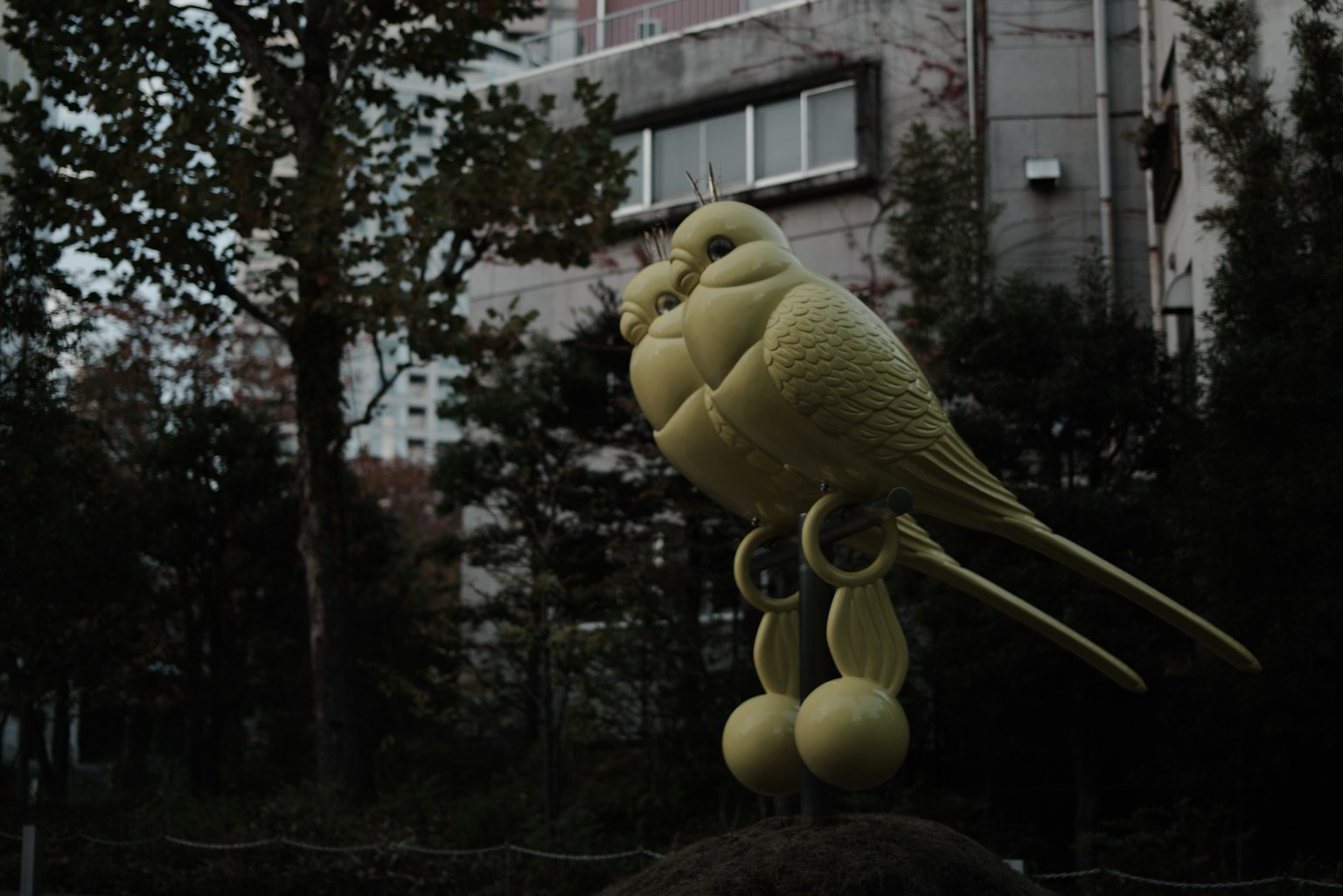一隻黃色鳥雕塑在城市背景下顯得突出