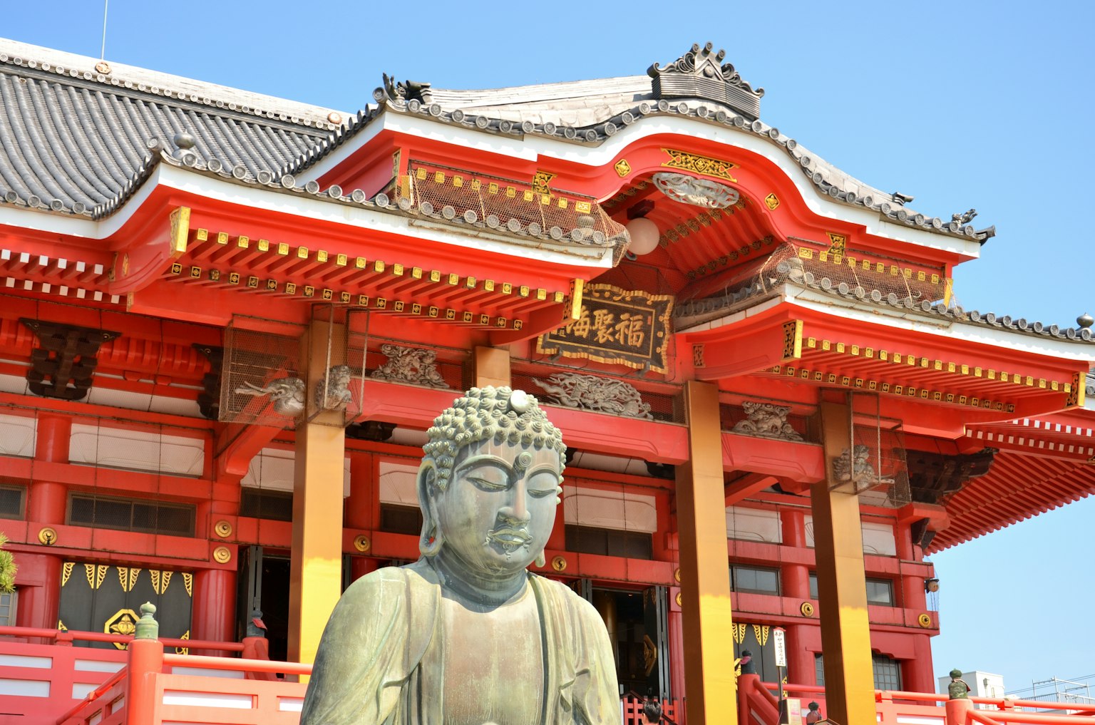 Large Buddha statue in front of a red temple