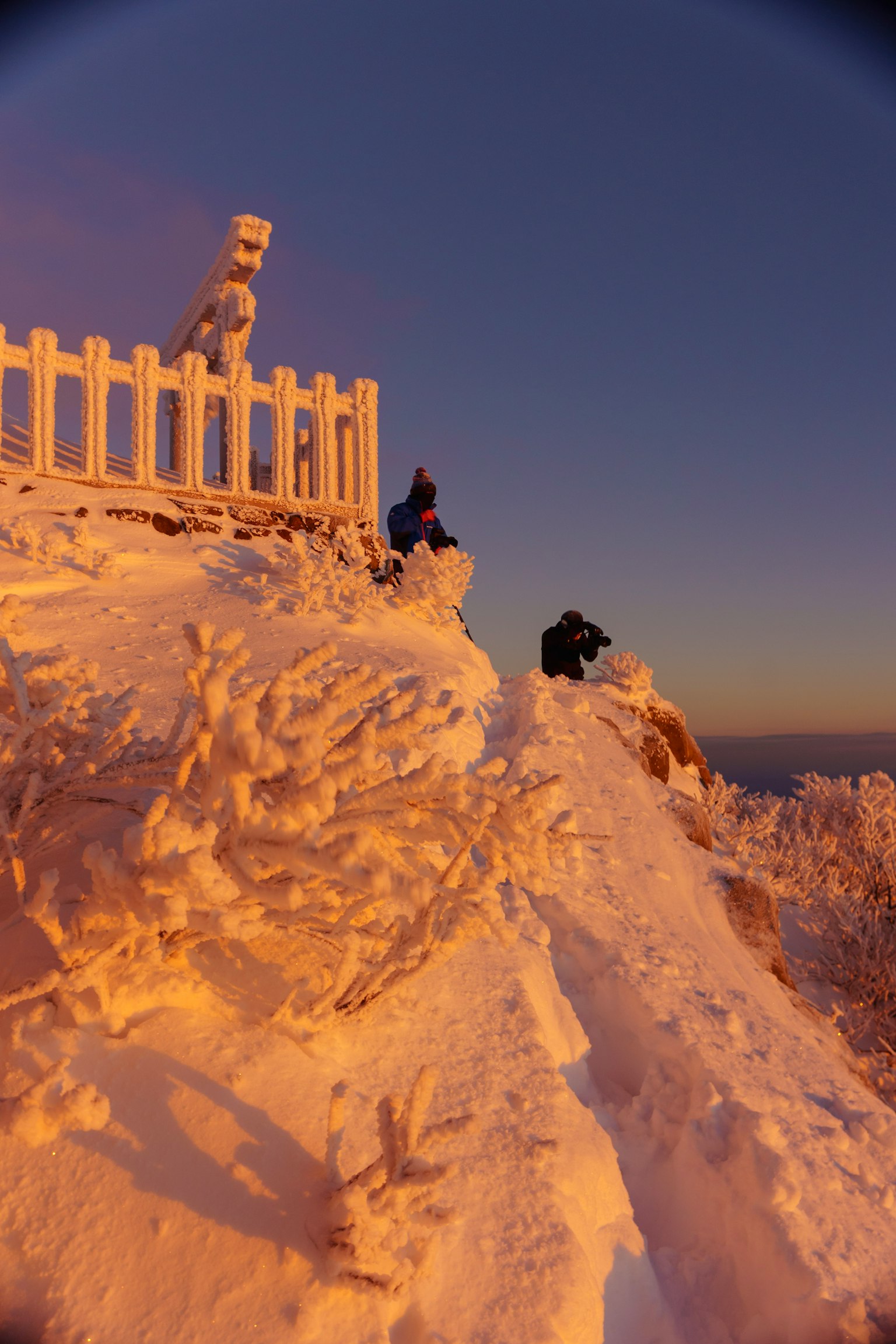 Schneebedeckter Berggipfel mit Sonnenuntergangslicht und Menschen