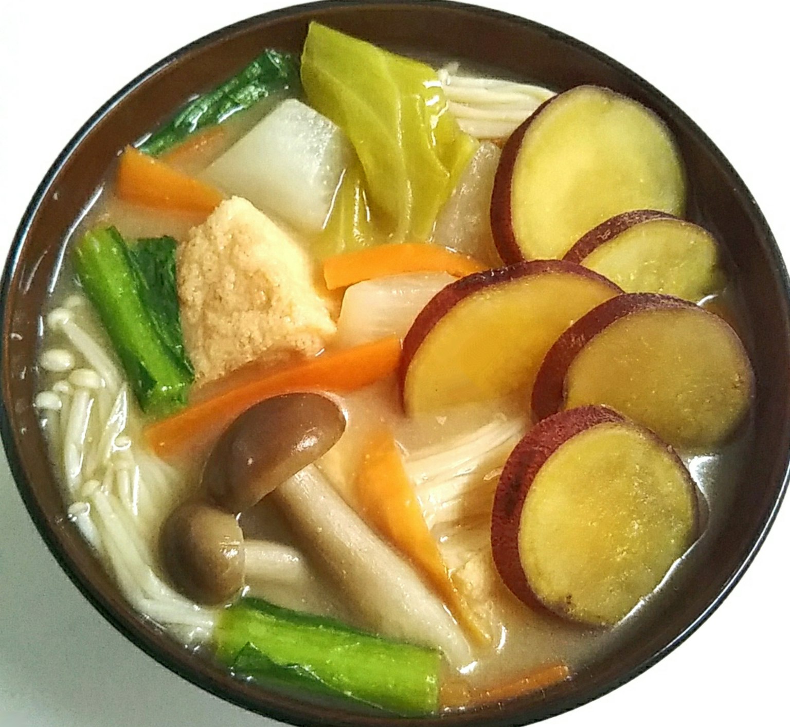 Un tazón de sopa con verduras coloridas y batatas