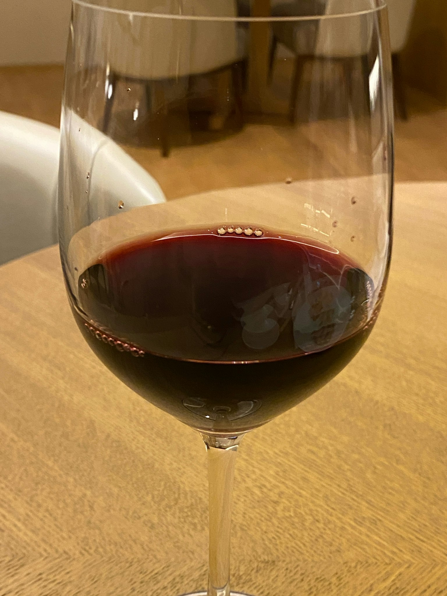 A wine glass filled with red wine placed on a wooden table