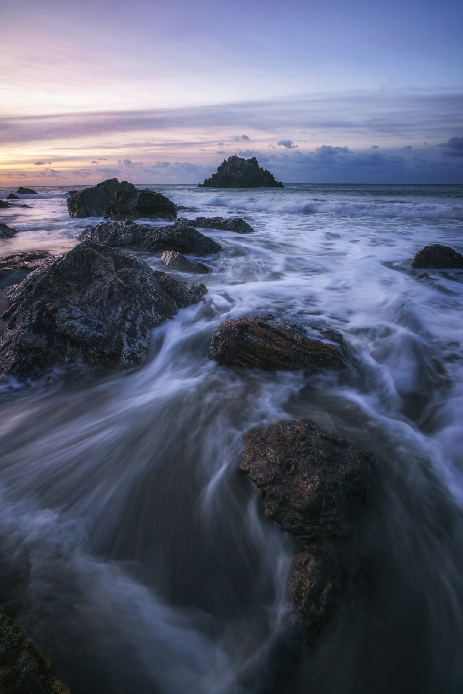 Beautiful sunset landscape with coastal rocks and flowing waves
