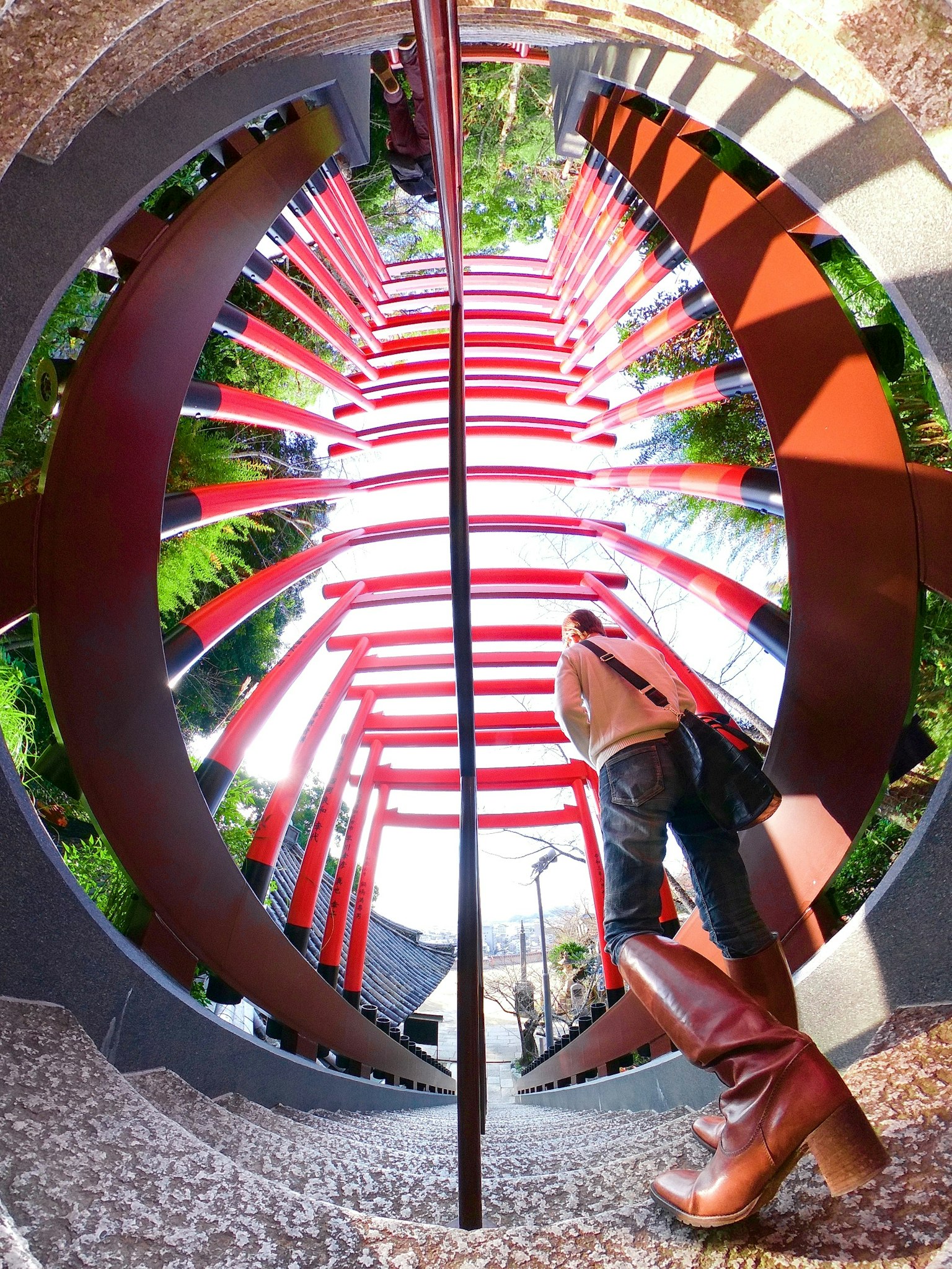 A woman standing in a unique structure featuring red stairs and green plants