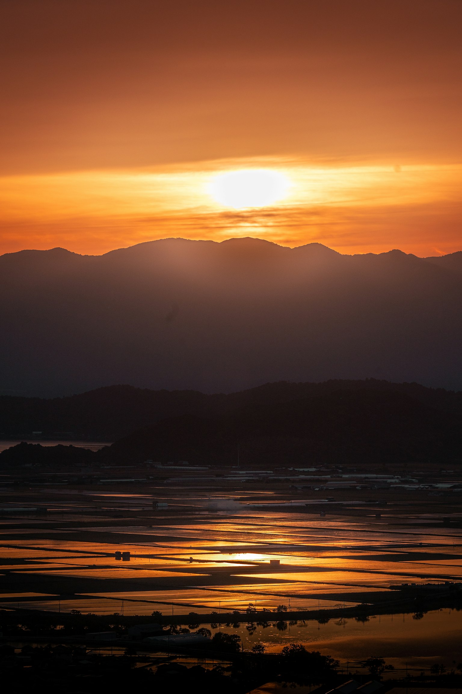 Splendida paesaggio con il sole al tramonto tra le montagne luce arancione che si riflette sulla superficie dell'acqua