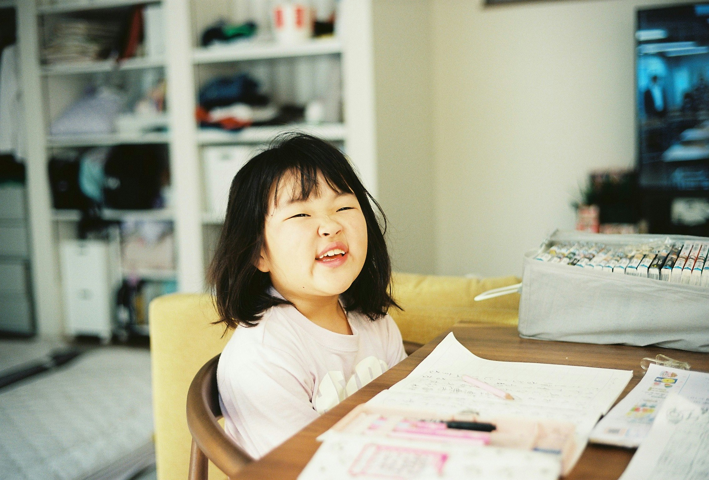 子供がテーブルで笑顔を見せている部屋の内部の写真