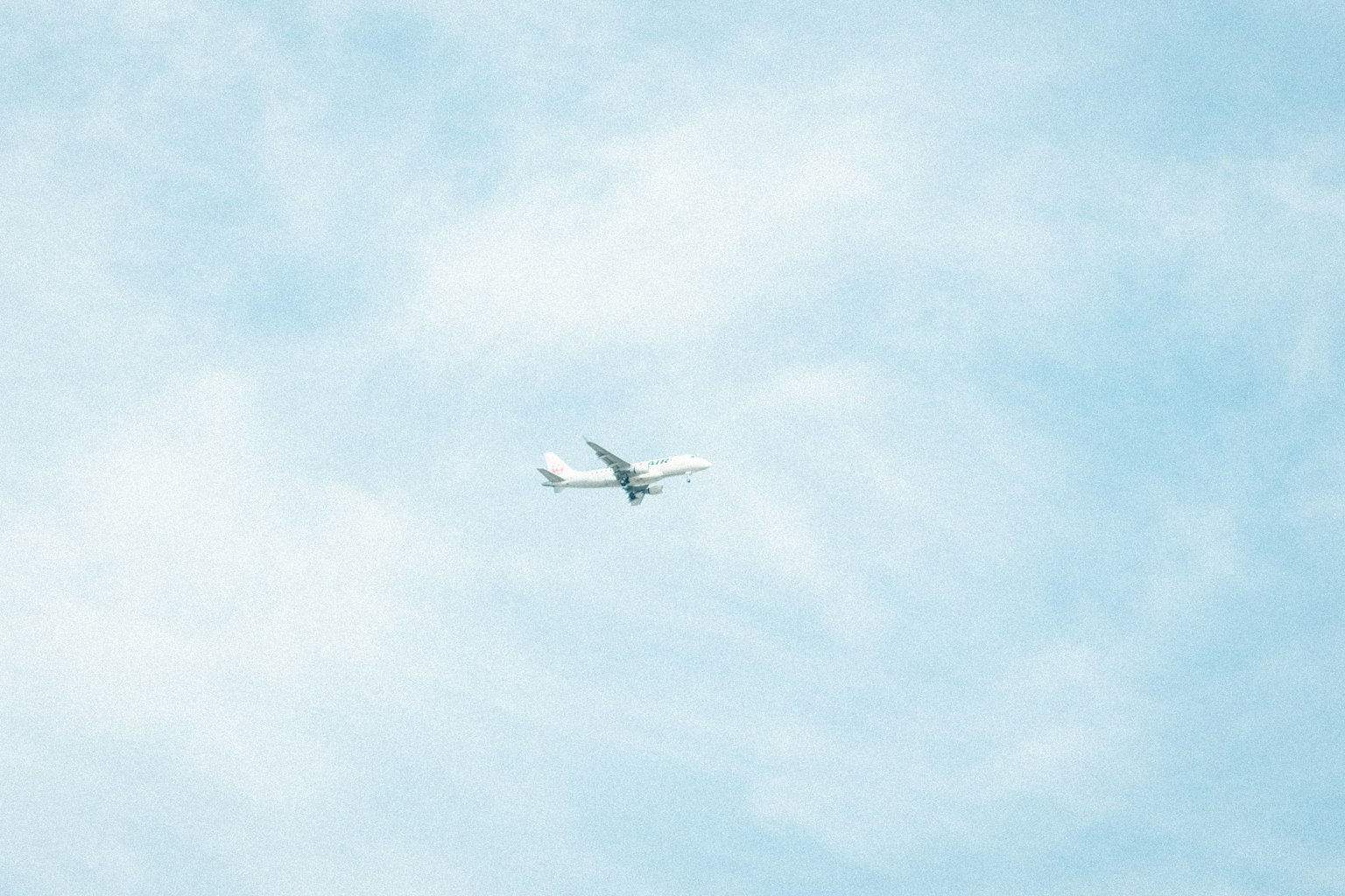 Pesawat putih terbang melawan langit biru