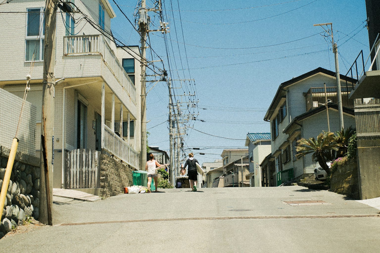 A person walking up a quiet slope in a residential area with houses