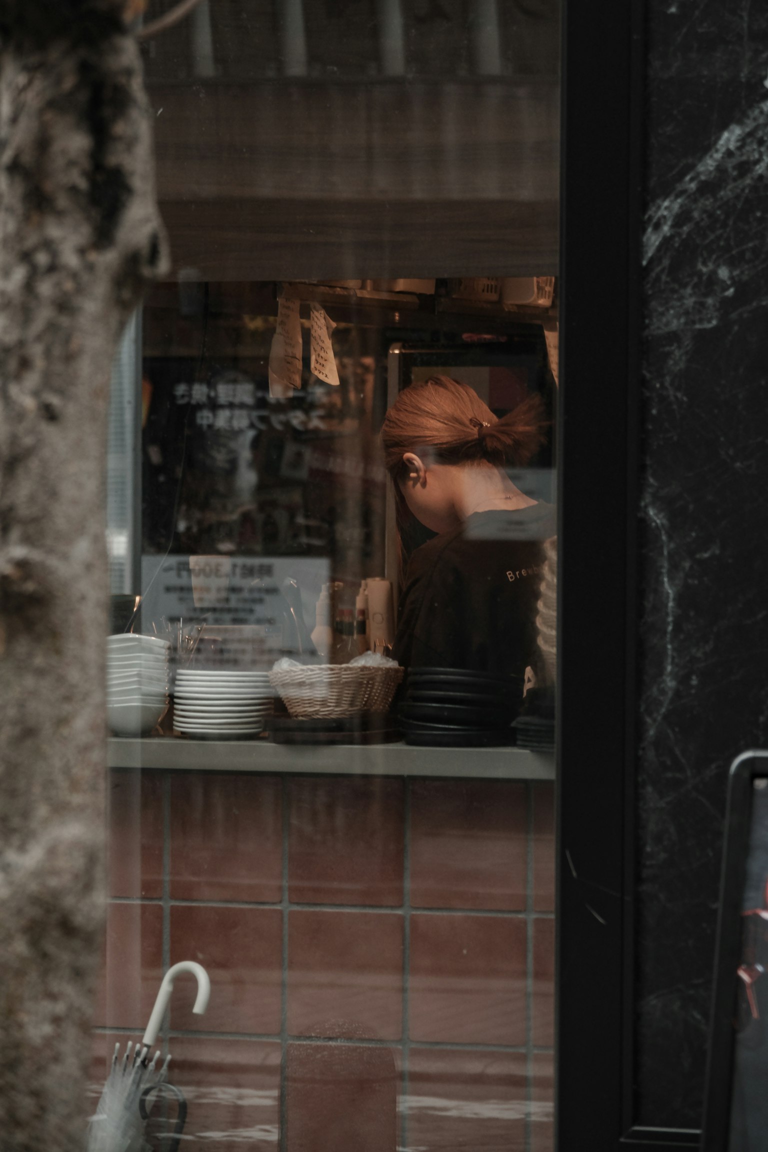 View through a window showing a chef preparing food inside a cozy kitchen