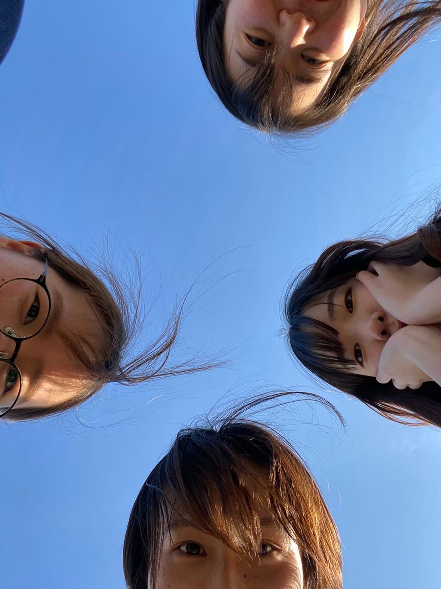 Four women showing their faces under a blue sky