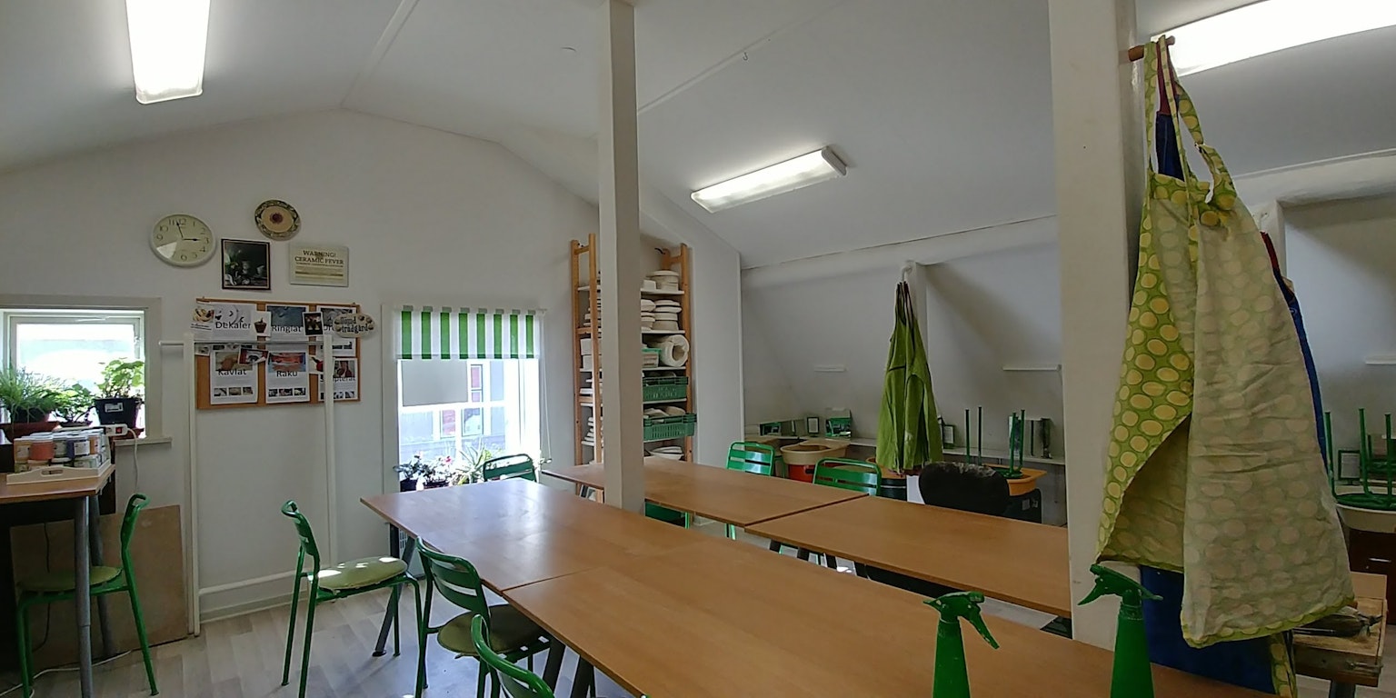 Interior kelas yang cerah dengan meja dan kursi tirai hijau dan apron