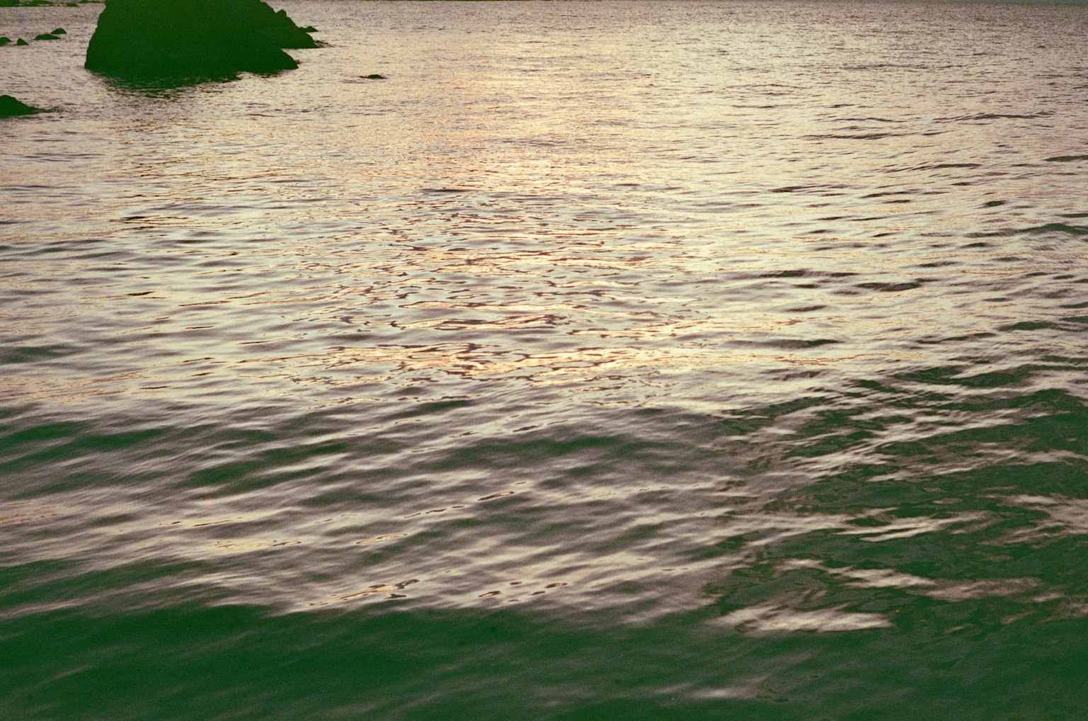 Superficie de agua ondulante reflejando el atardecer sobre el mar