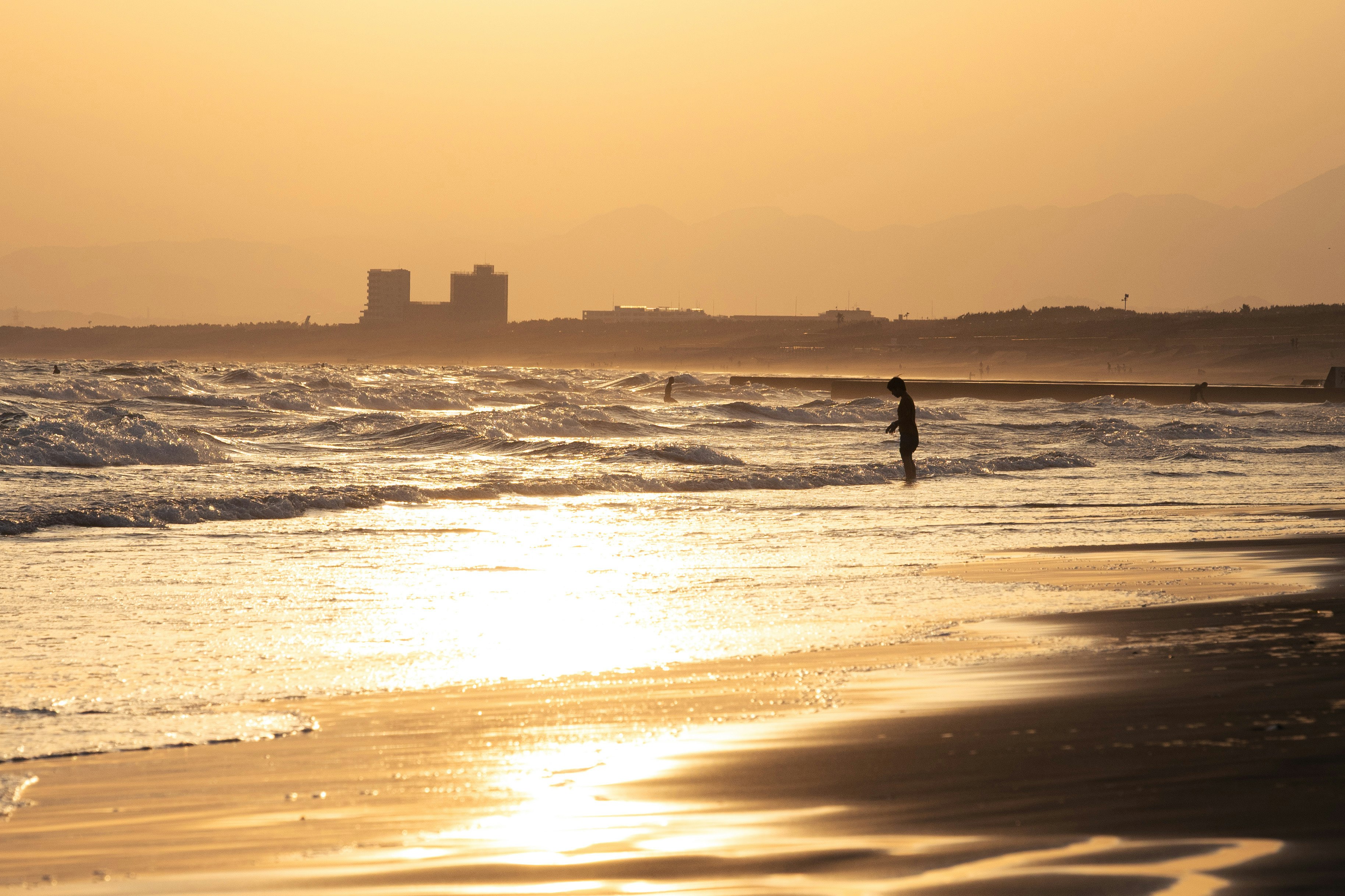 夕日に照らされた海辺の砂浜と一人の人物