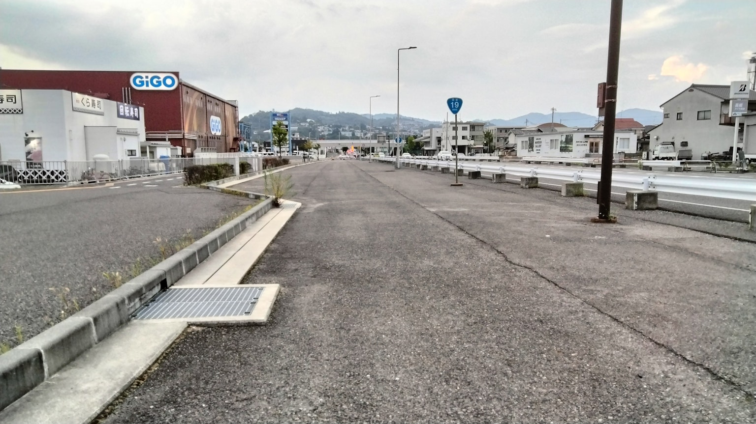 Breite Straße mit umliegenden Gebäuden und Bergen im Hintergrund