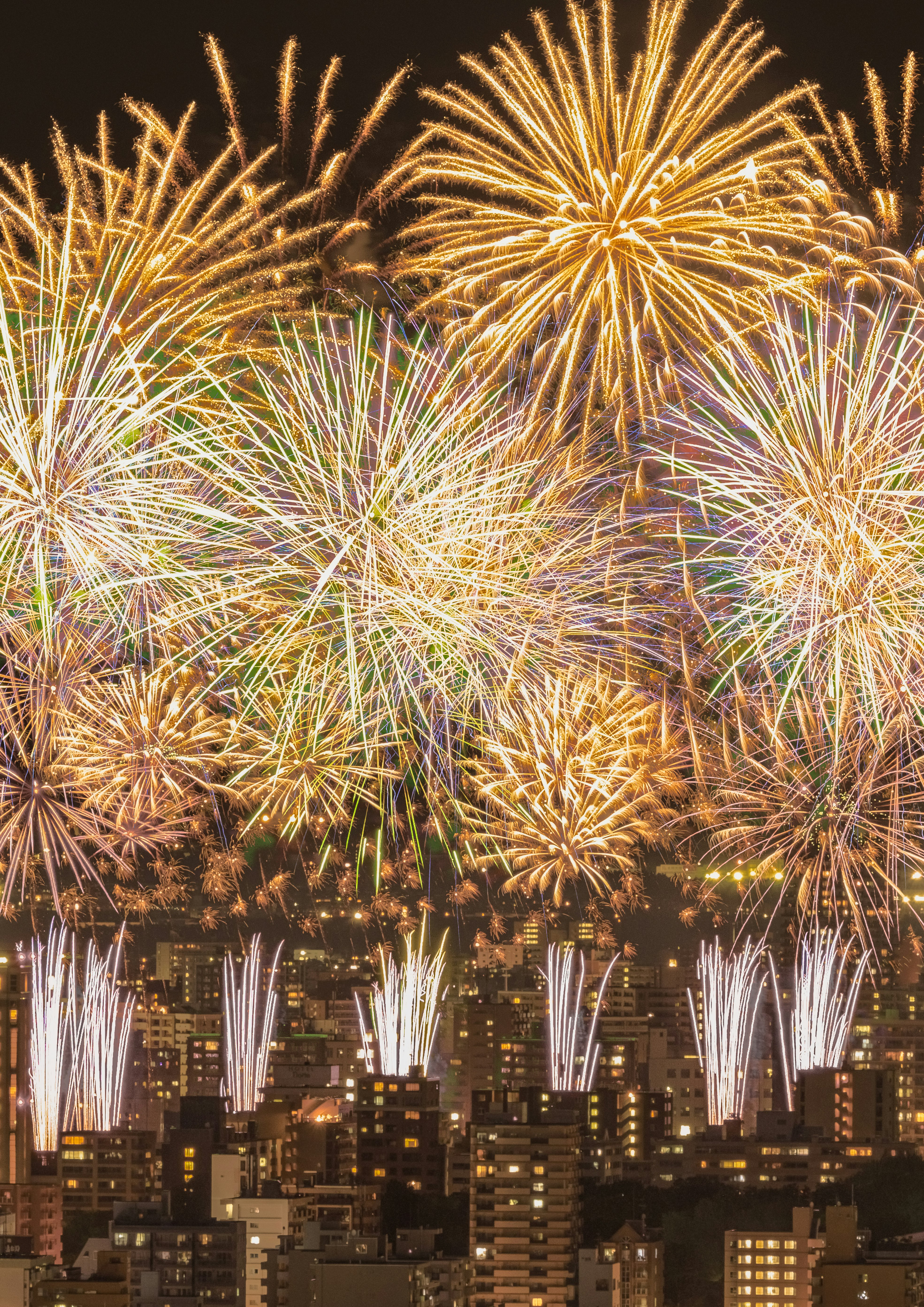夜空に広がる色とりどりの花火が都市のビル群の上で輝いている
