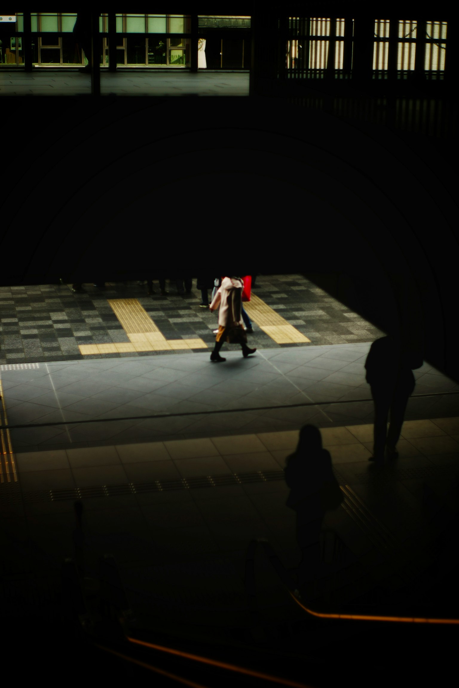 Una persona in un abito rosso si trova su un pavimento illuminato in un ambiente scuro