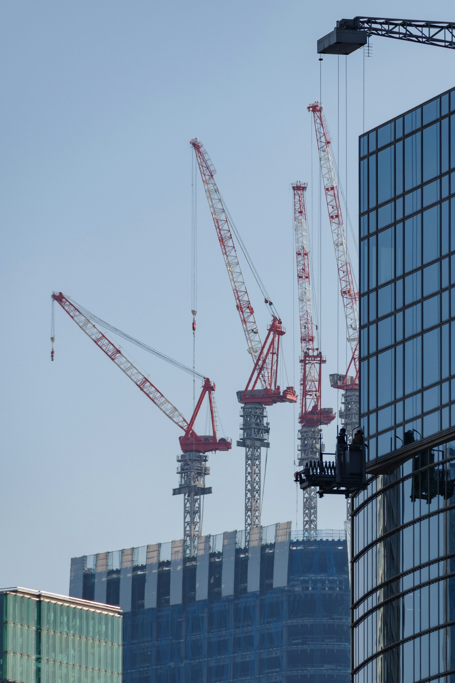 高樓建設工地上的紅色起重機和附近的現代建築