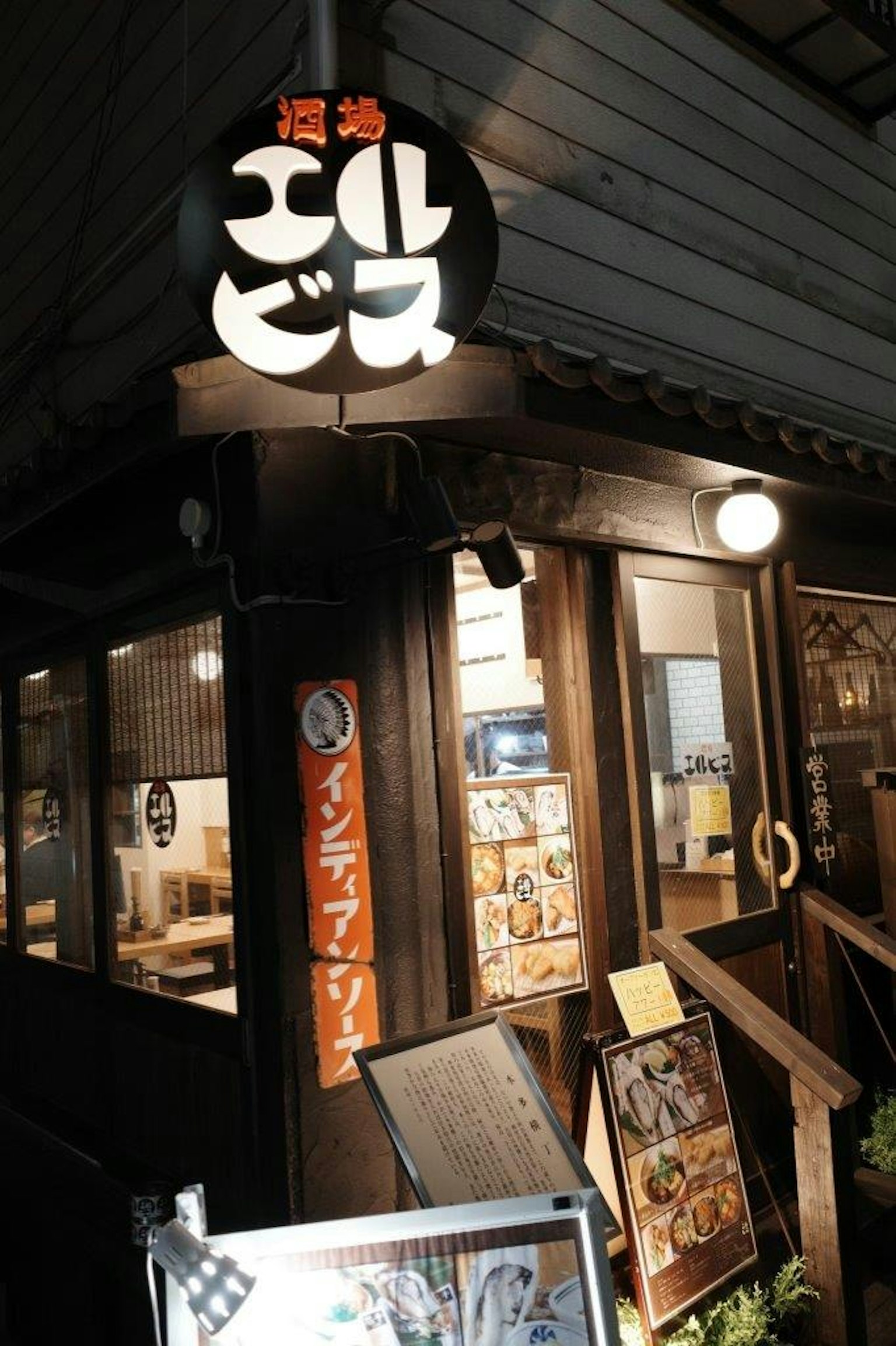 Extérieur d'un restaurant japonais la nuit avec un panneau lumineux et une structure en bois
