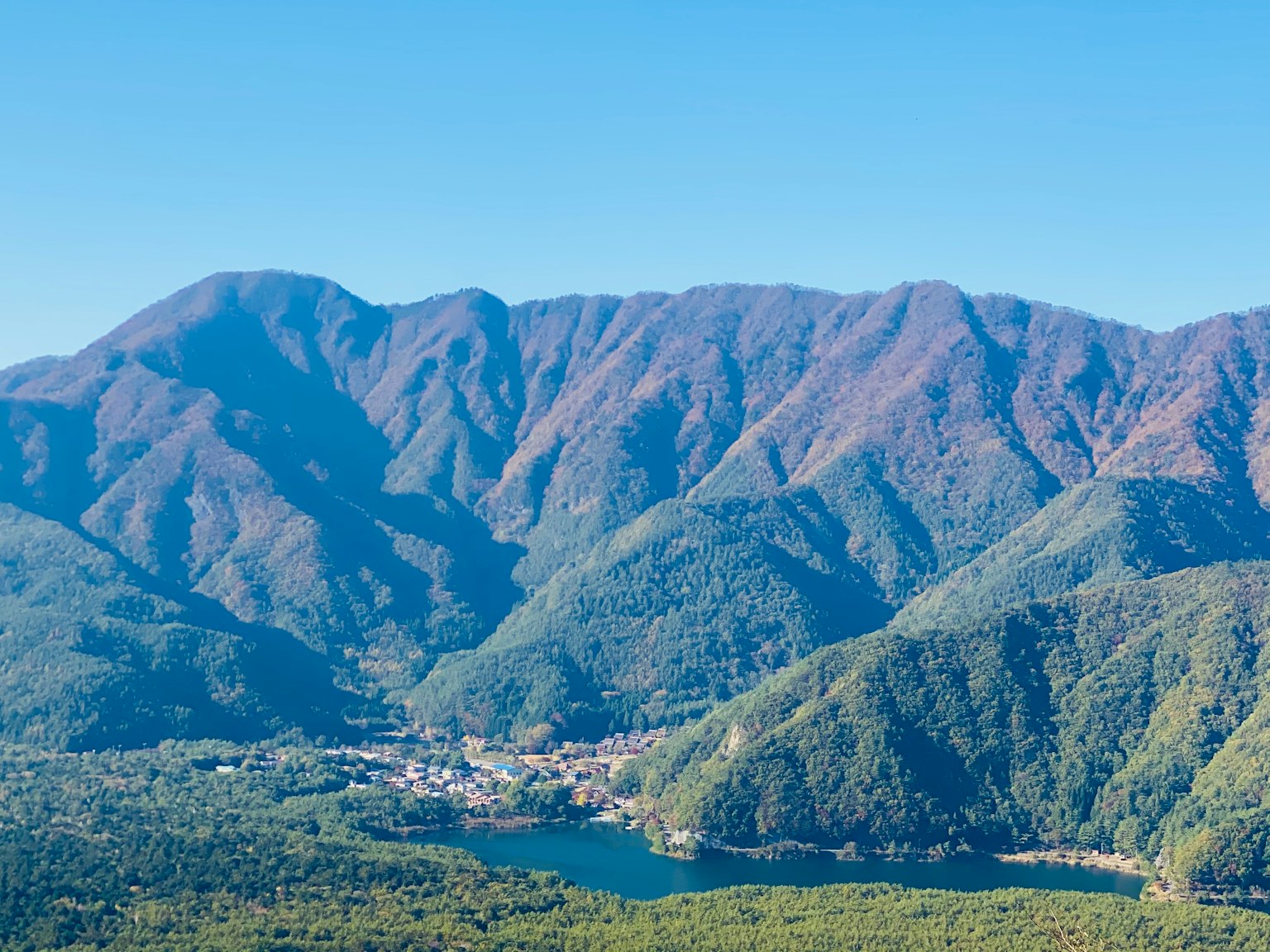 在晴朗蓝天下郁郁葱葱的群山和小镇的全景