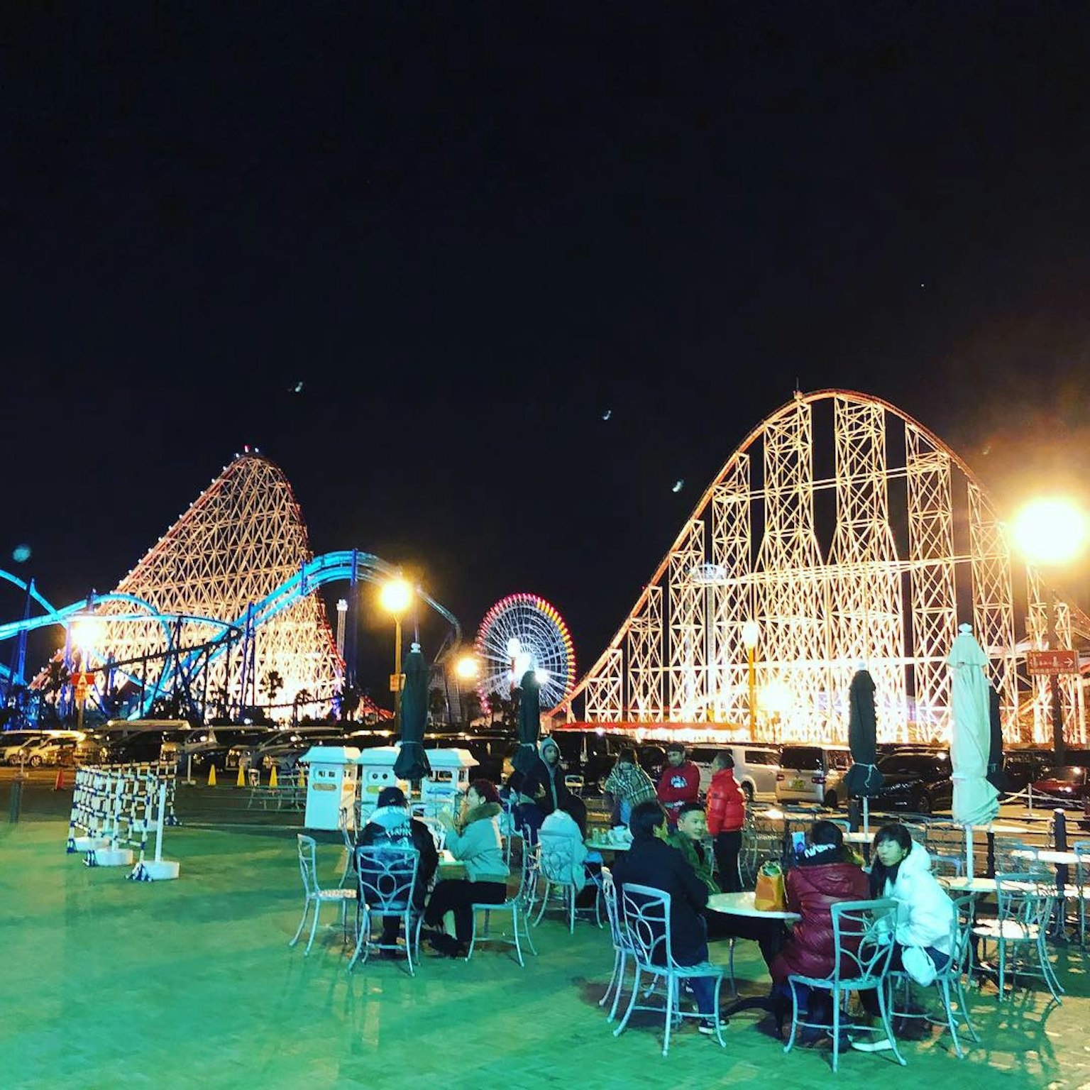 Pemandangan malam taman hiburan dengan roller coaster dan bianglala