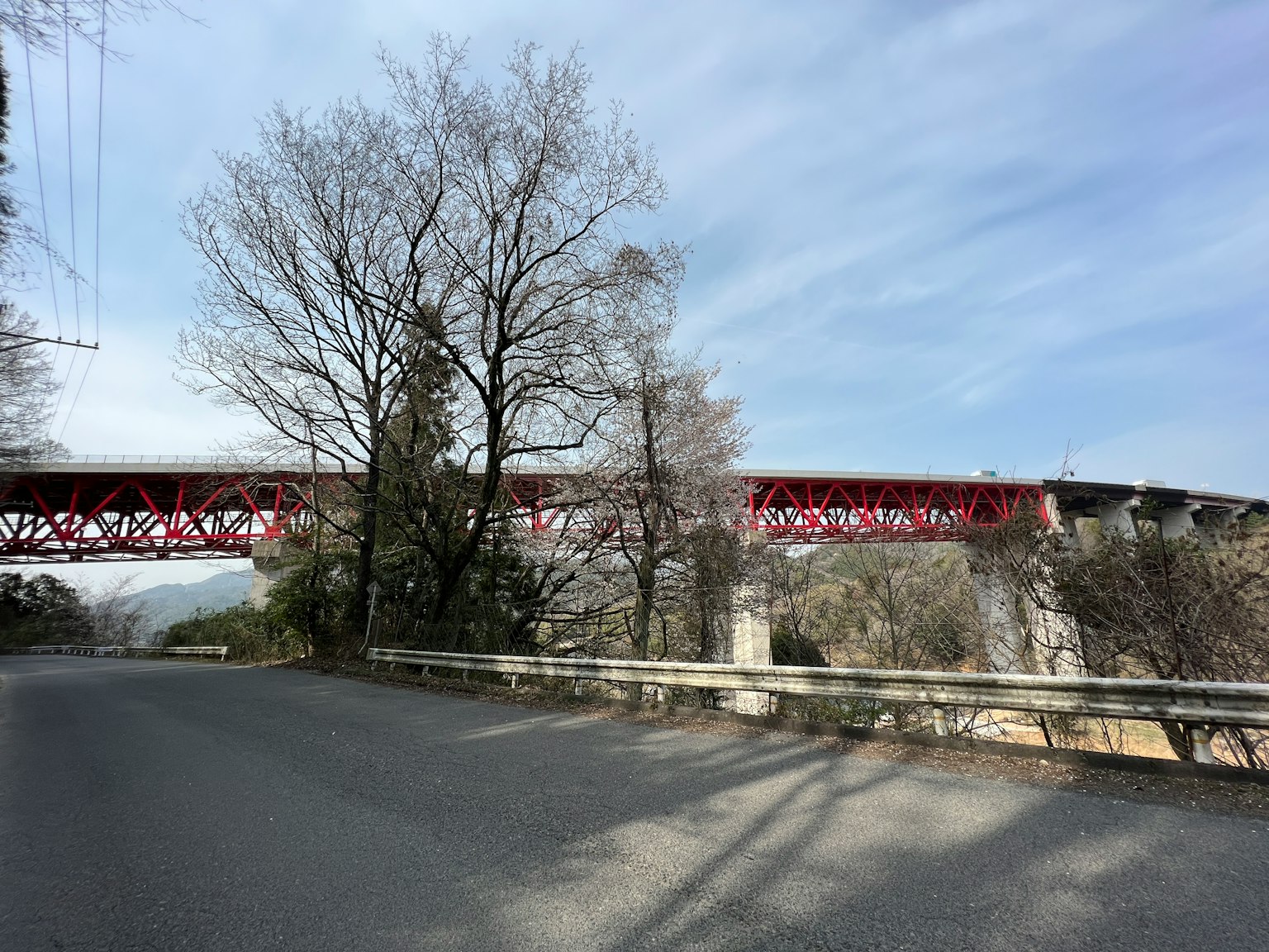Pont ferroviaire rouge entouré d'arbres et d'un ciel clair