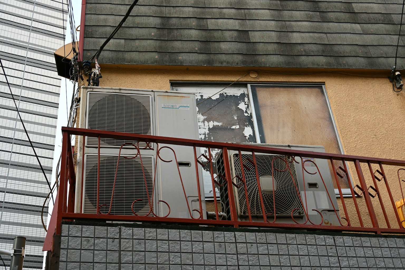 Unités de climatisation sur un balcon d'un vieux bâtiment avec fenêtre écaillée