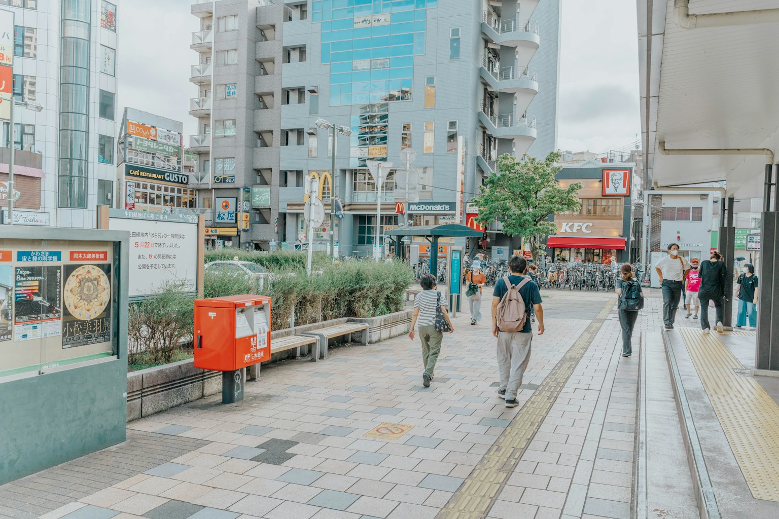 Urban scene with people walking on the street commercial buildings and a public transport stop visible