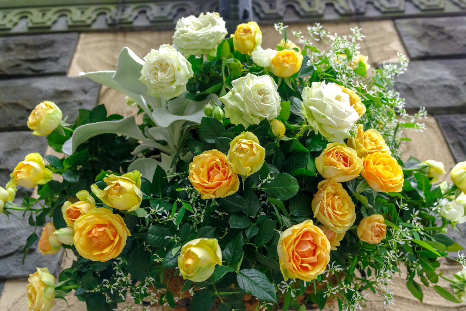 Ein Strauß aus gelben und weißen Rosen umgeben von üppigem Grün
