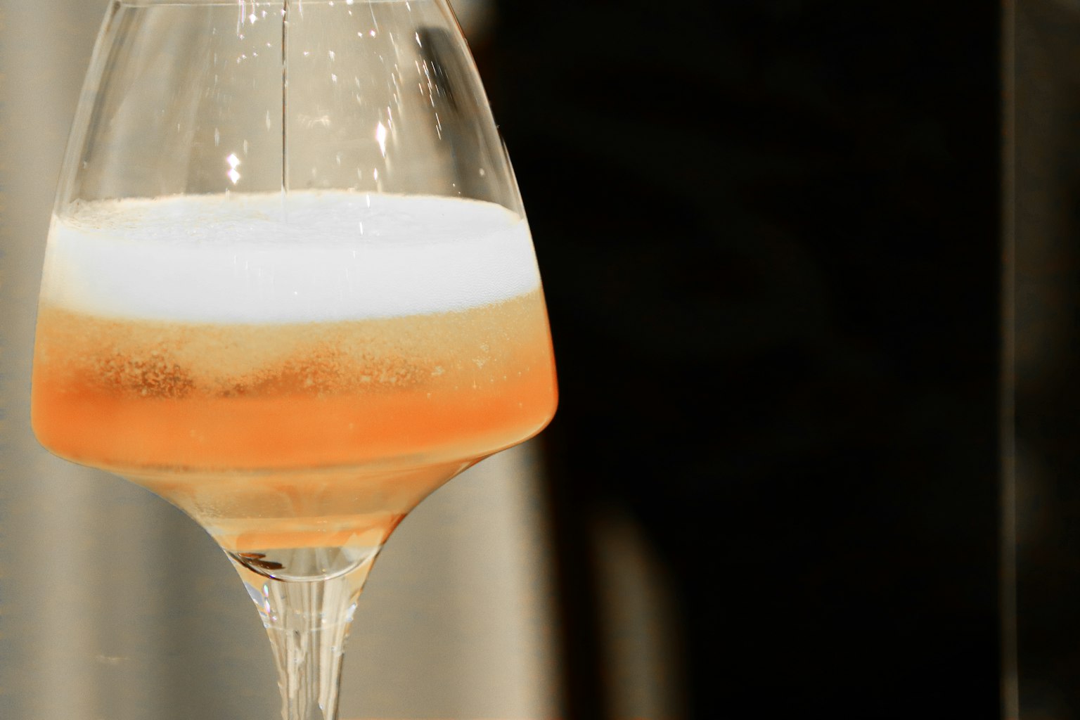 Un bicchiere con una bevanda stratificata che presenta arancione e schiuma bianca