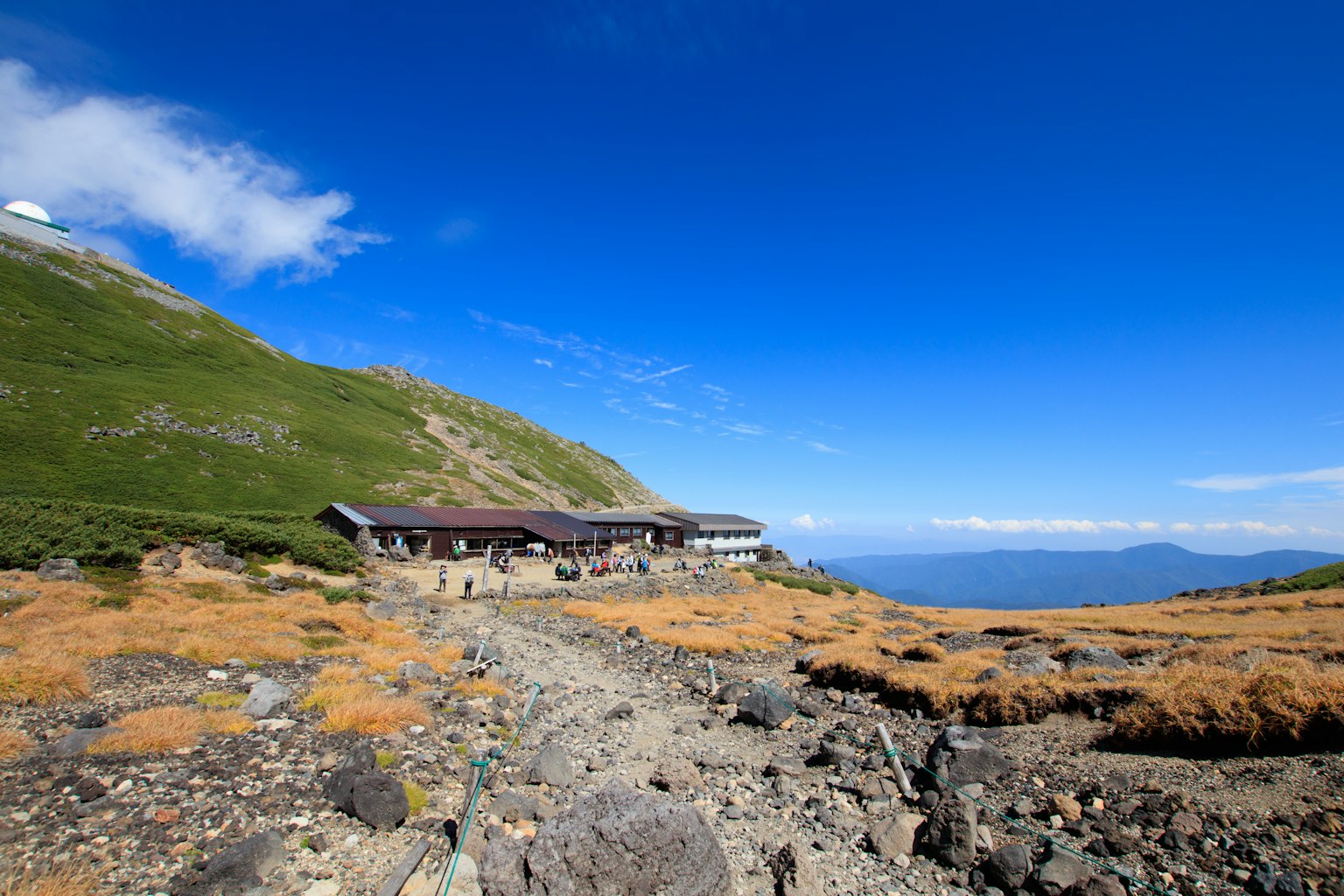 Berglandschaft unter blauem Himmel mit einer Hütte