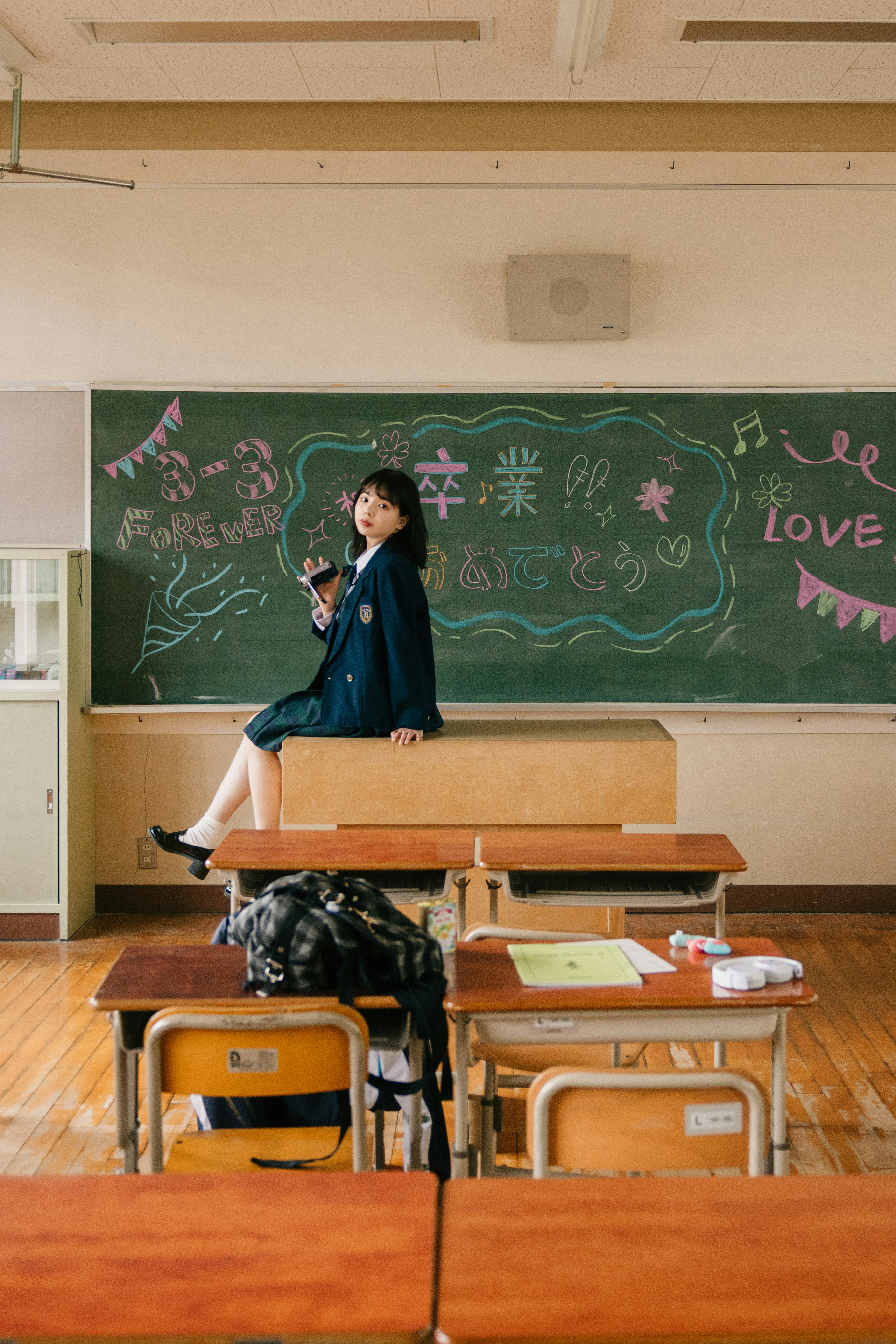 黒板の前で椅子に座る制服姿の子どもがいる教室