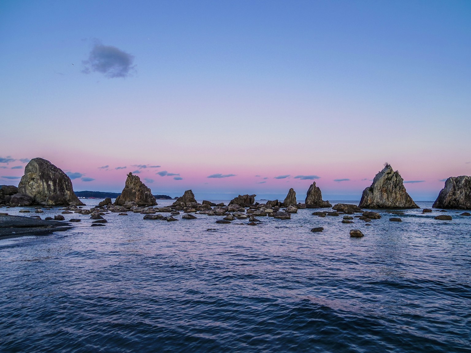 Costa rocciosa con acque calme e colori del tramonto