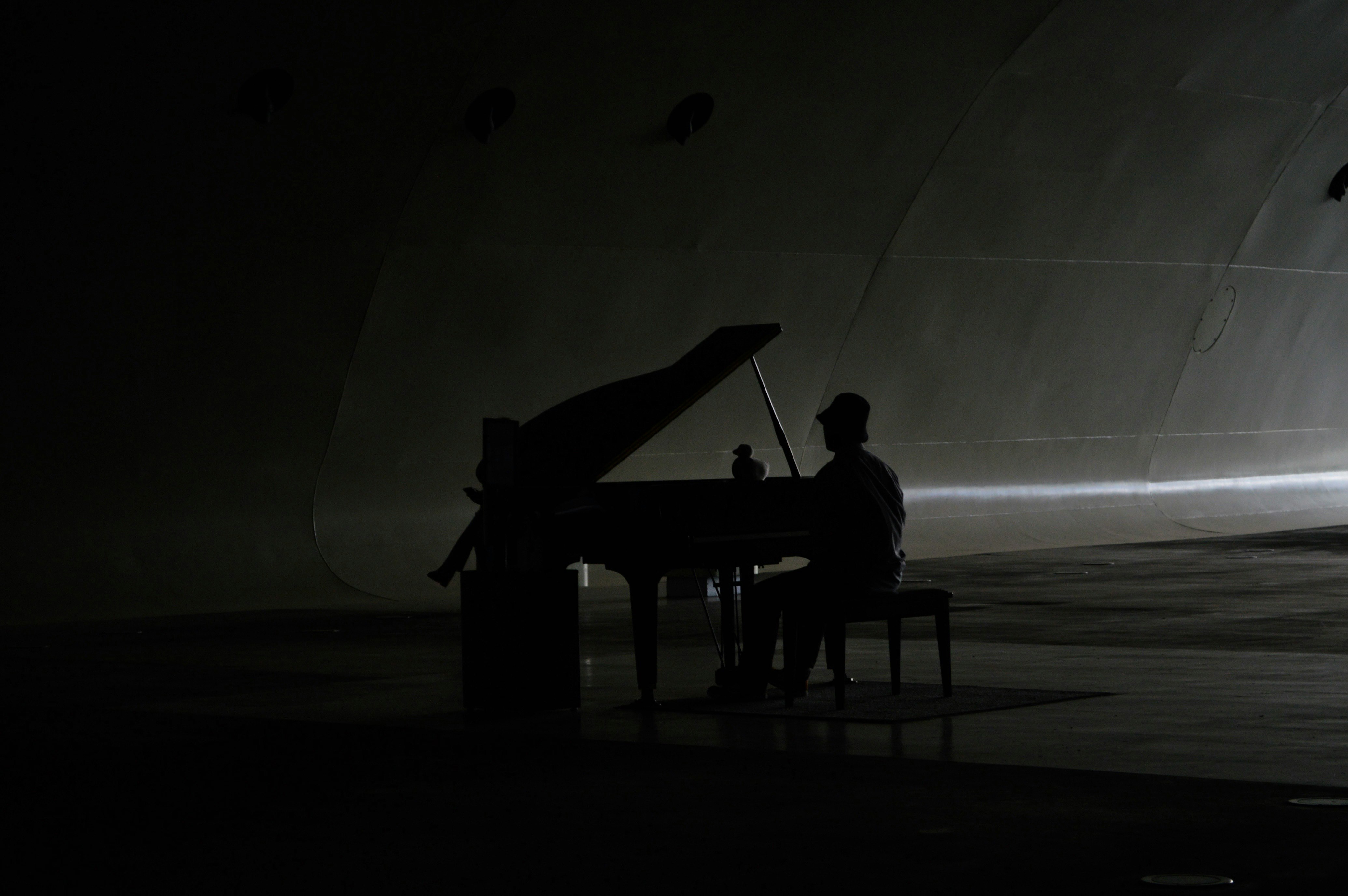 silhouette d’un pianiste jouant un piano dans un théâtre sombre