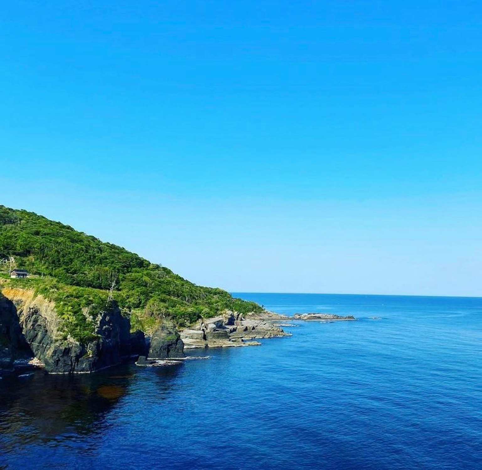 Scenic view of a blue sea and green hillside