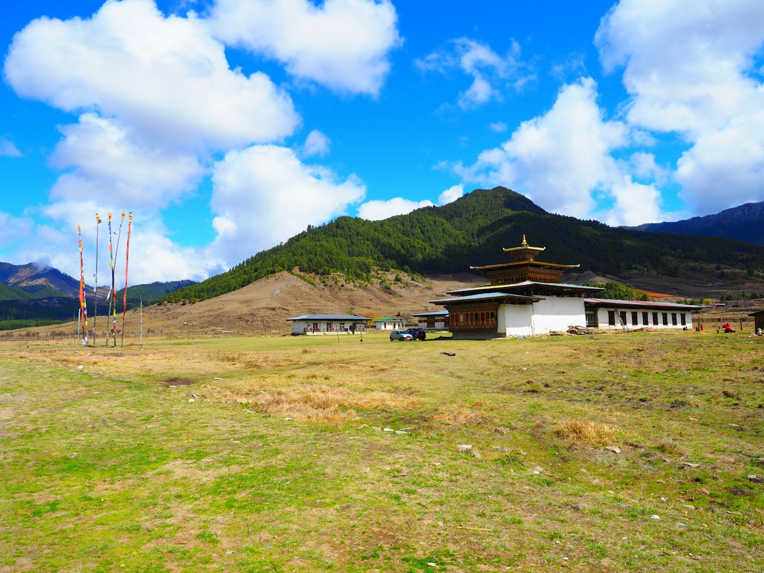 Un temple entouré de plaines herbeuses et de montagnes sous un ciel bleu