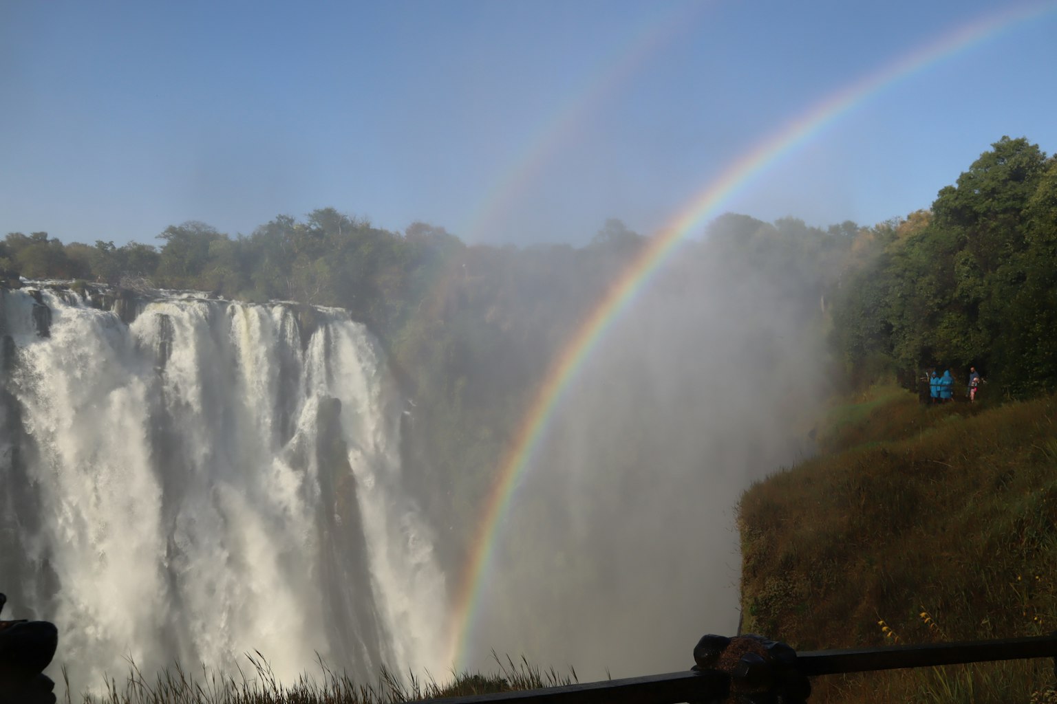 Doppio arcobaleno sopra una cascata con vegetazione lussureggiante