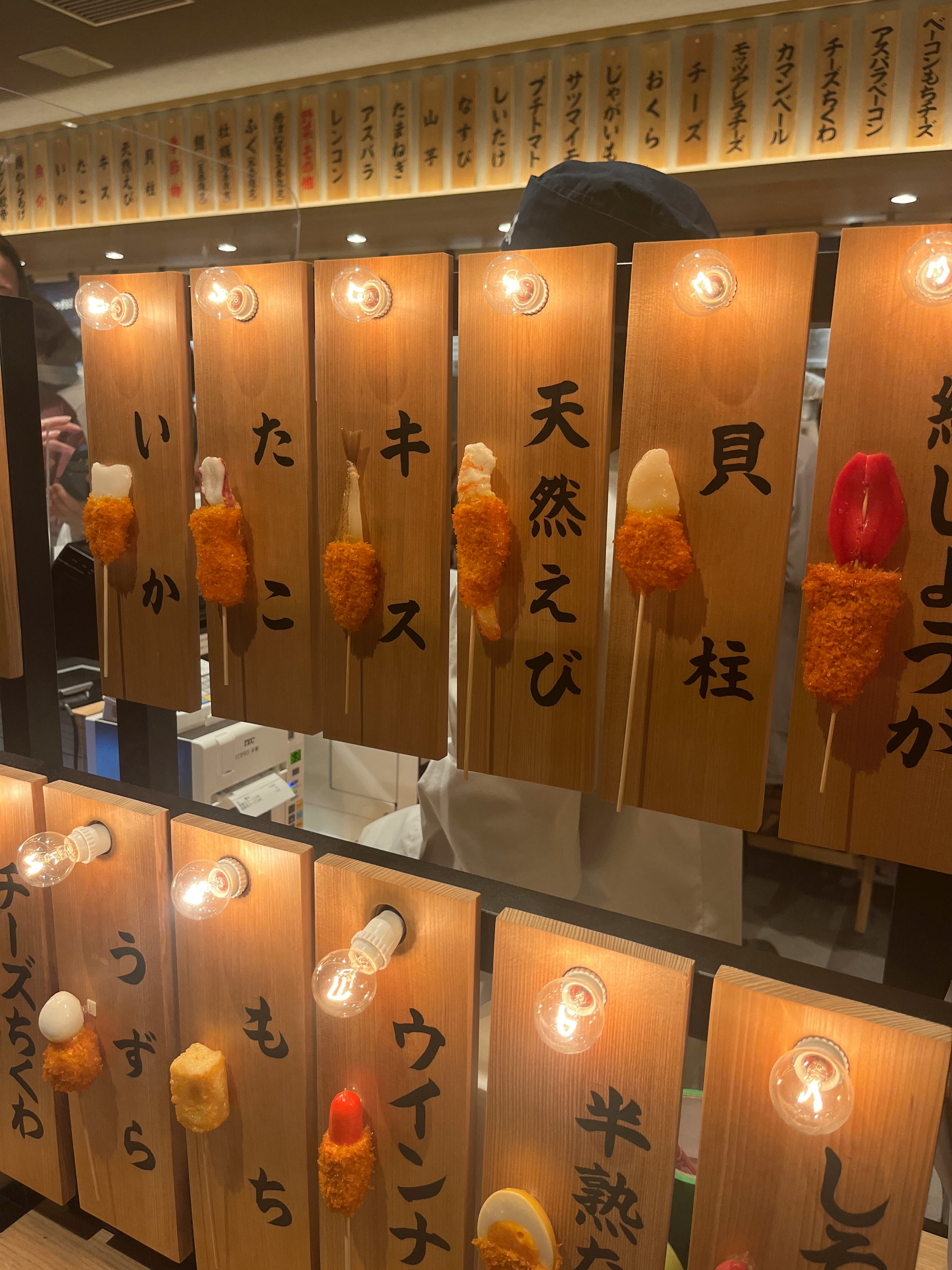 串カツだるまの店内で吊るされた木札と串揚げの飾り