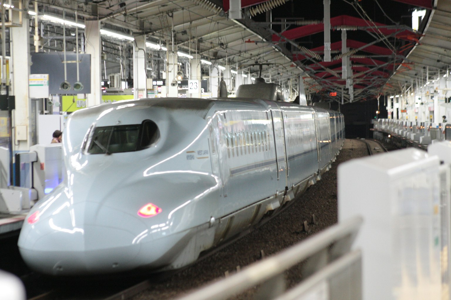 Tren Shinkansen en una estación, exterior gris brillante, techo de la estación visible