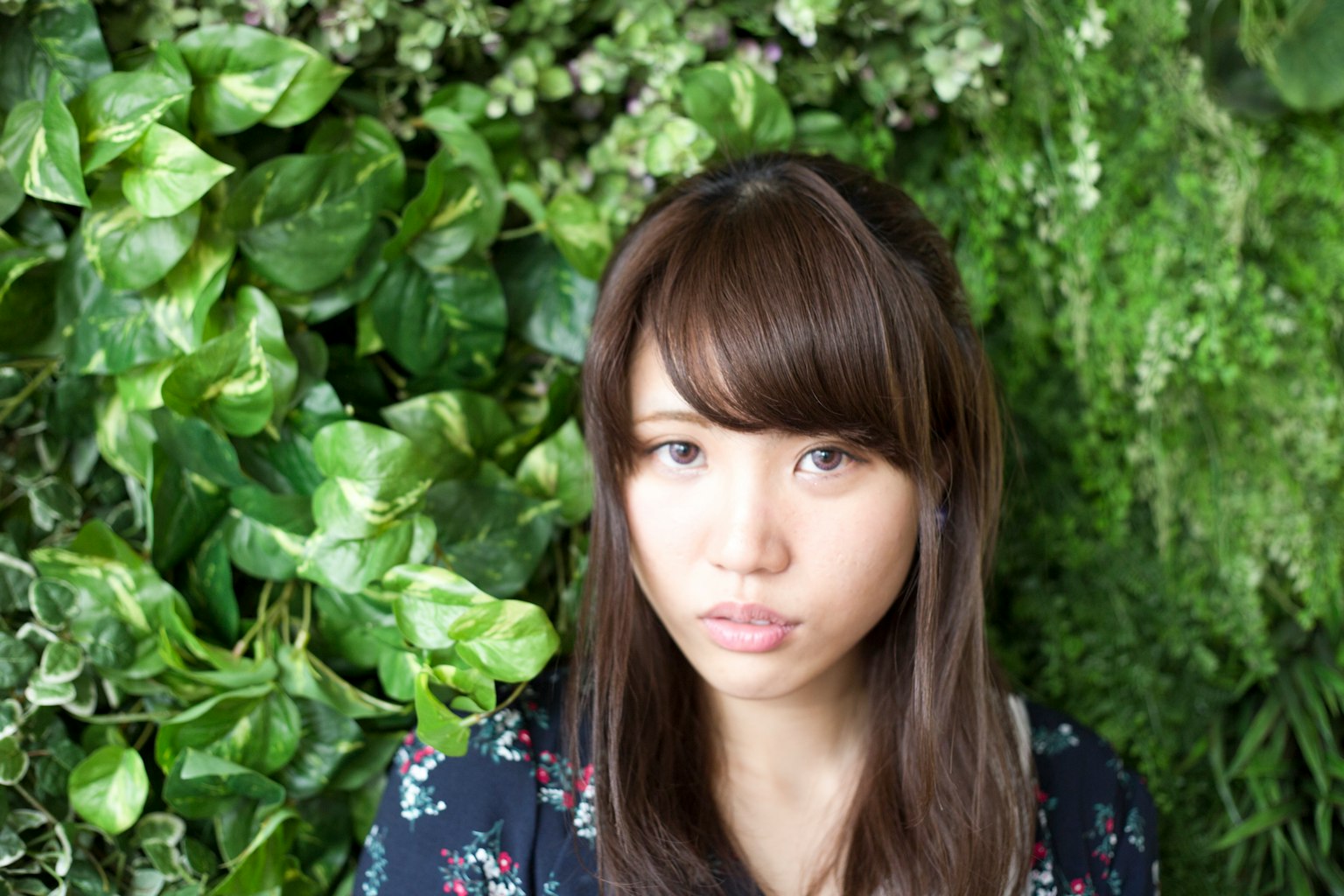 Portrait of a young woman sitting in front of a green wall