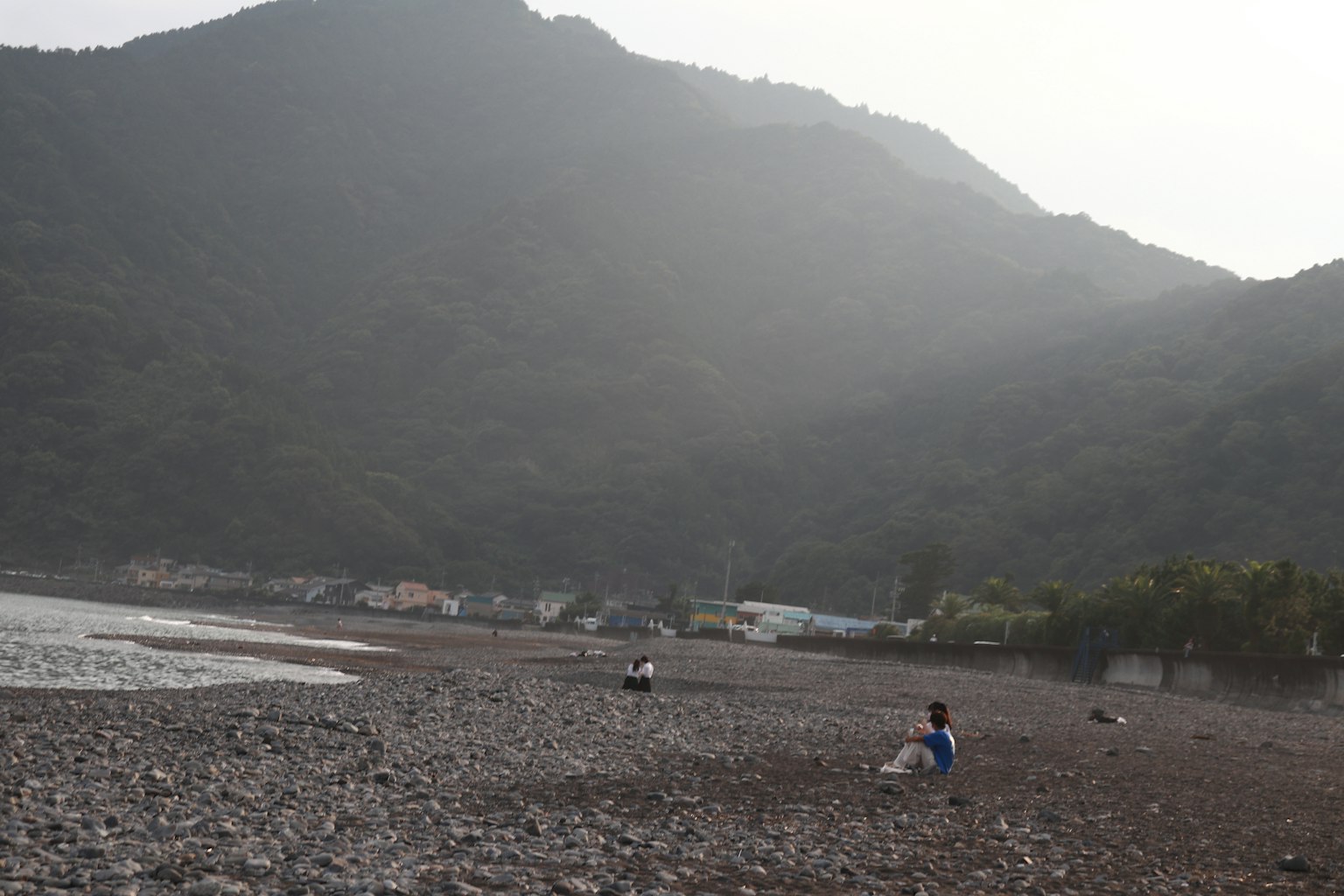 岩石海滩和背景中的山脉以及放松的人们