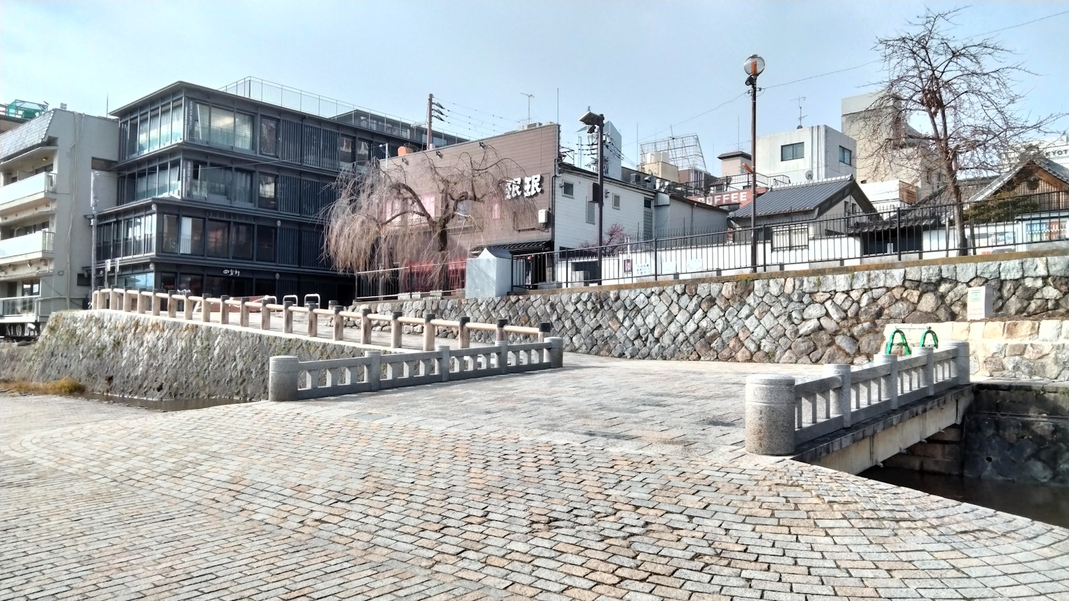 Quiet scene featuring a stone bridge and modern buildings