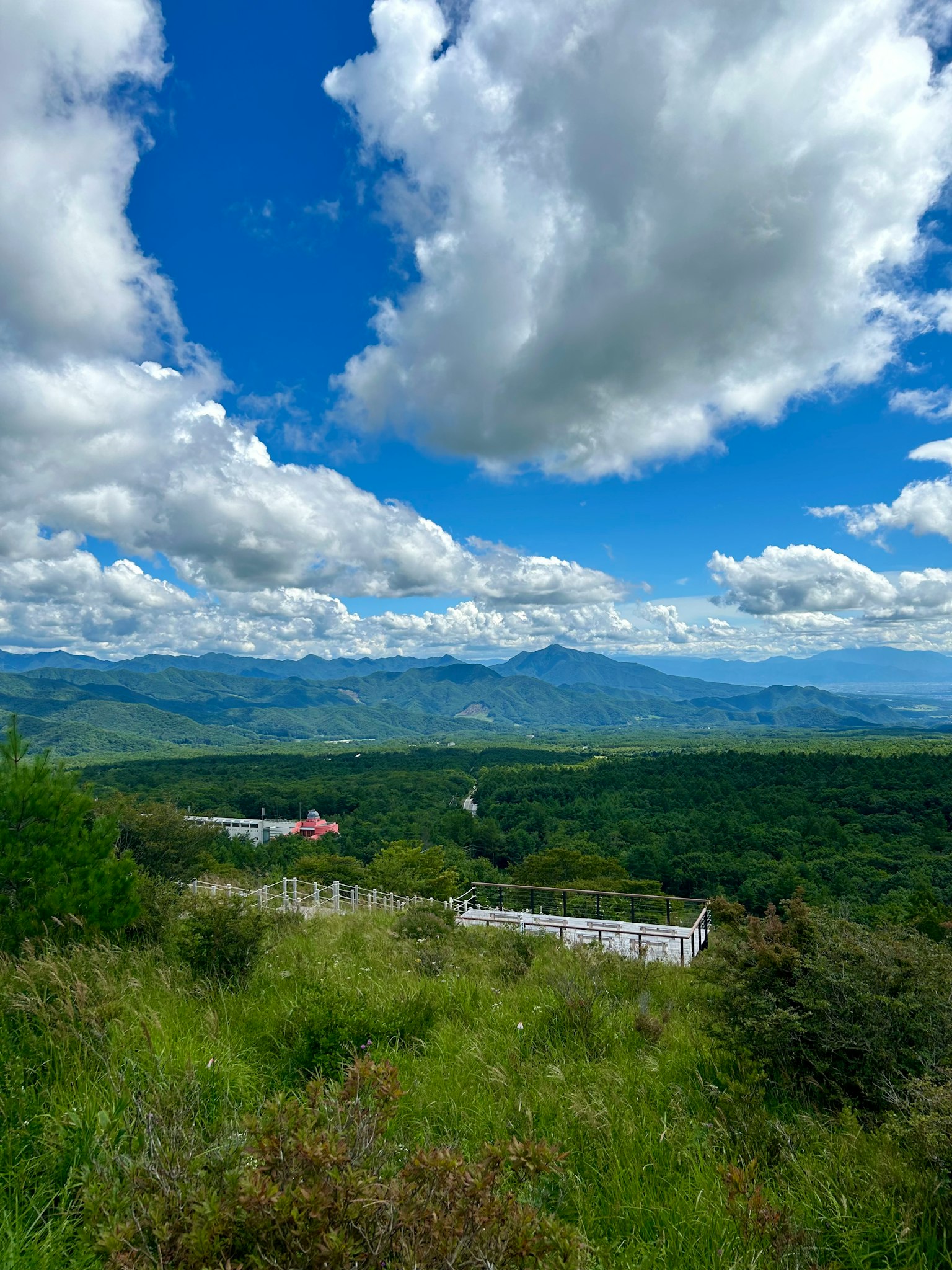 Panoramablick auf Berge unter blauem Himmel mit Wolken üppigen grünen Hügeln und sichtbaren Häusern