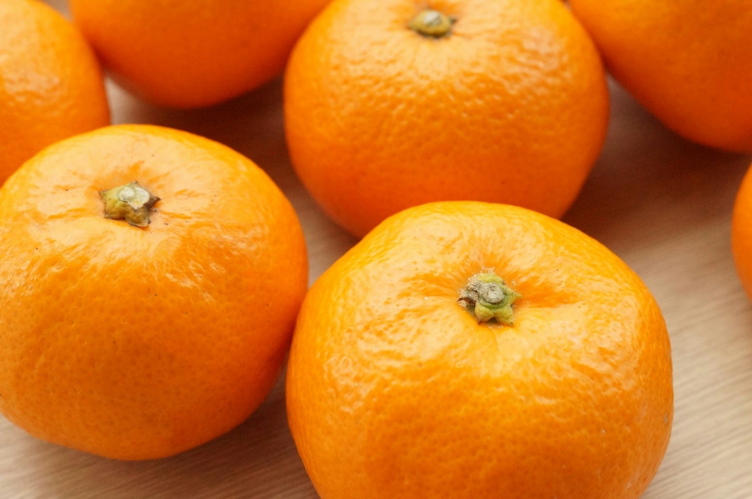 Gambar close-up dari jeruk mandarin oranye cerah yang disusun di atas permukaan kayu