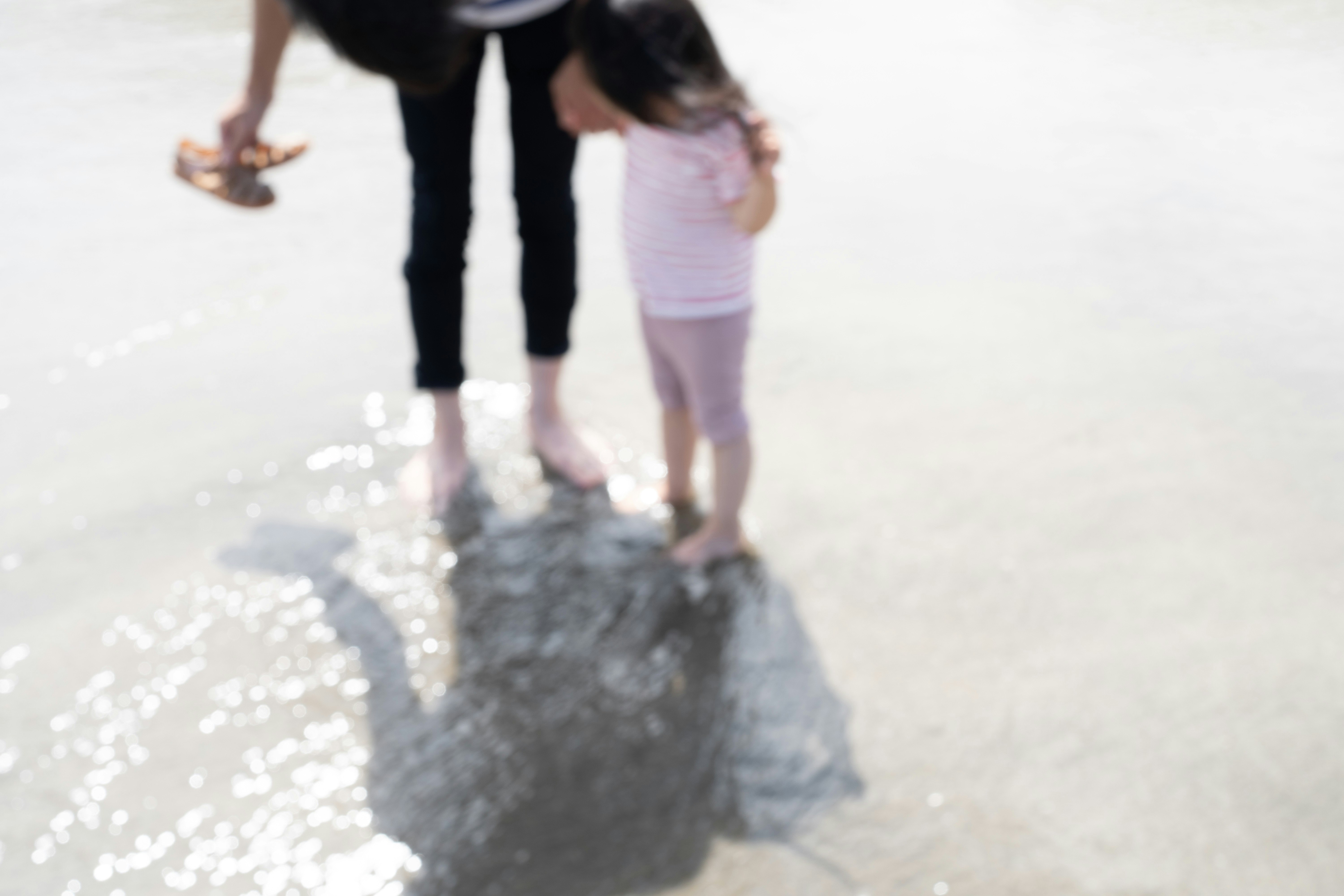 Sommermoment am Meer: Elternteil und Kind planschen im Wasser
