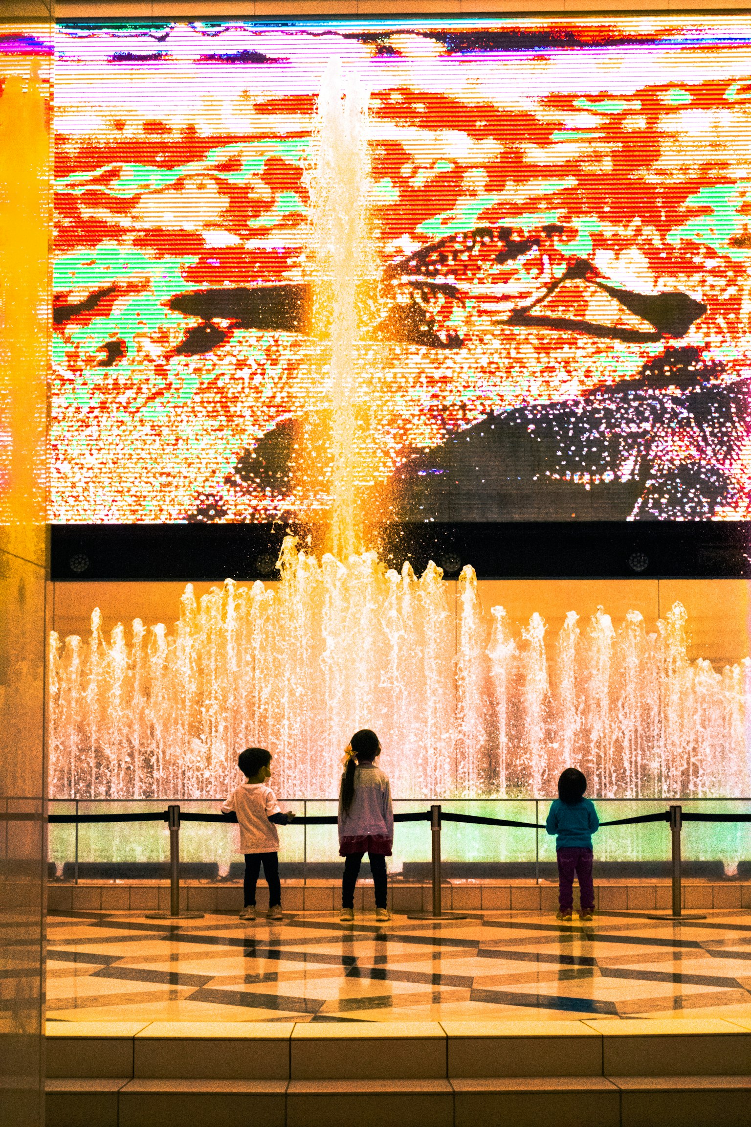 Enfants se tenant devant un spectacle de lumière coloré et une fontaine